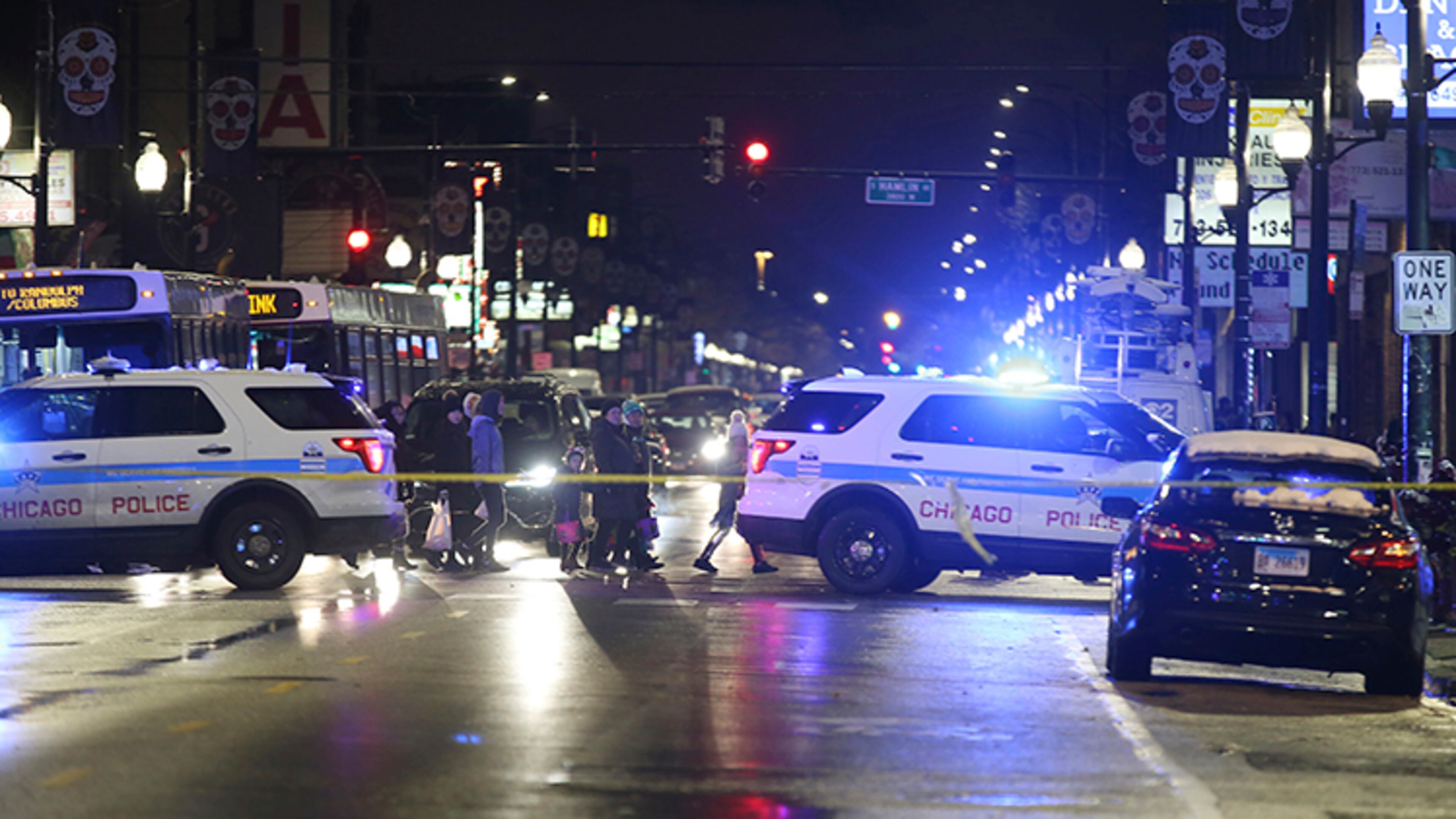 Trick-or-treaters walk past a crime scene in the 3700 block of West 26th Street, where a 7-year-old girl was shot while trick-or-treating, in Chicago.