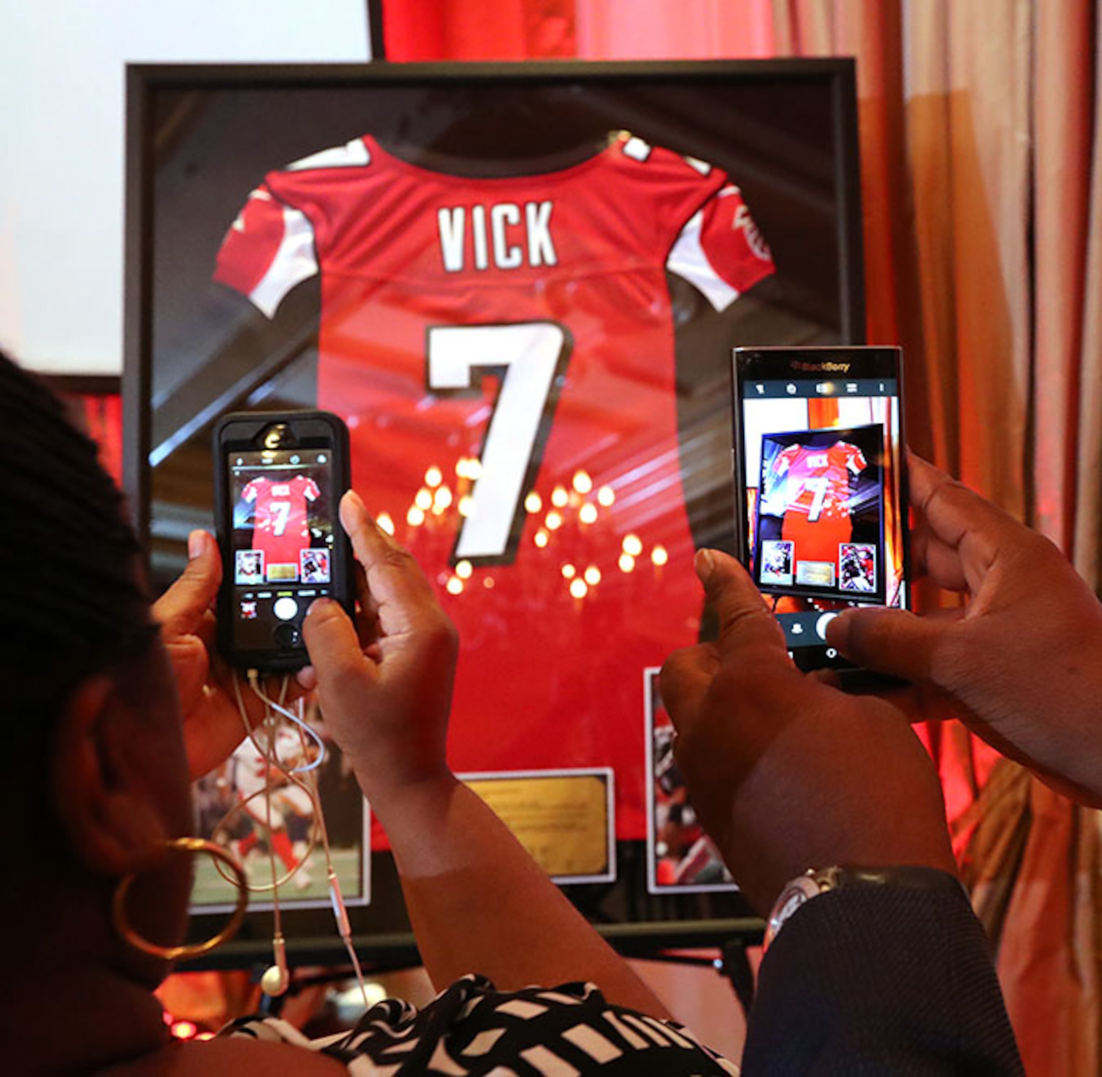 June 12, 2017, Atlanta: Attendees snap photos of Michael Vickââ¬â¢s framed jersey while the Atlanta Falcons honor former Falcons quarterback Michael Vick and wide receiver Roddy White as they officially retire from the NFL on Monday, June 12, 2017, in Atlanta. Curtis Compton/ccompton@ajc.com