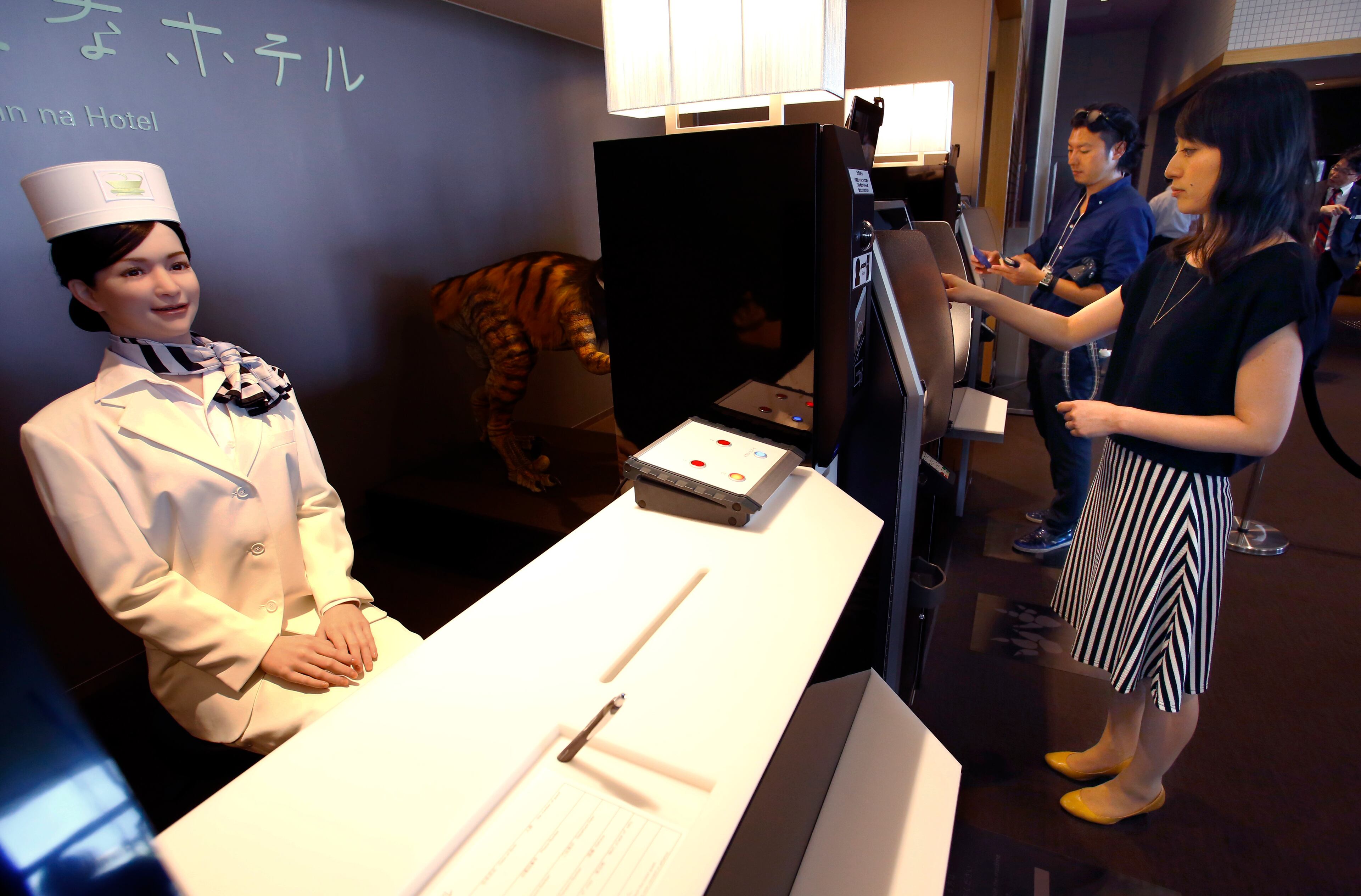 A receptionist robot, left, greets a hotel employee, right, demonstrating how to check in for the media at the new hotel, aptly called Henn na Hotel or Weird Hotel, in Sasebo, southwestern Japan, Wednesday, July 15, 2015. From the receptionist that does the check-in and check-out to the porter that’s a stand-on-wheels taking luggage up to the room, the hotel, that is run as part of Huis Ten Bosch amusement park, is “manned” almost totally by robots to save labor costs. (AP Photo/Shizuo Kambayashi)