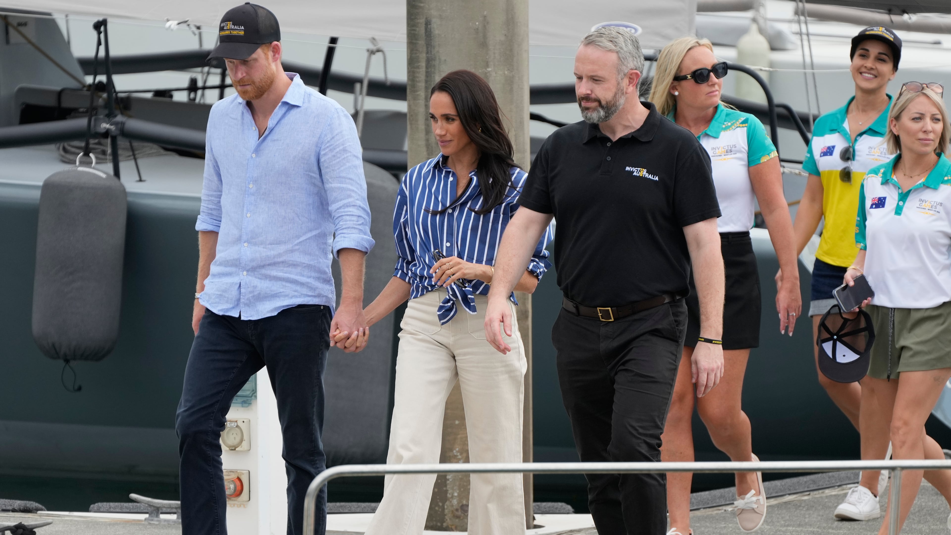 FILE - Prince Harry, left, and his wife Meghan, the Duke and Duchess of Sussex, arrive at a dock after sailing on the harbor in Sydney, Friday, April 17, 2026. (AP Photo/Rick Rycroft, File)