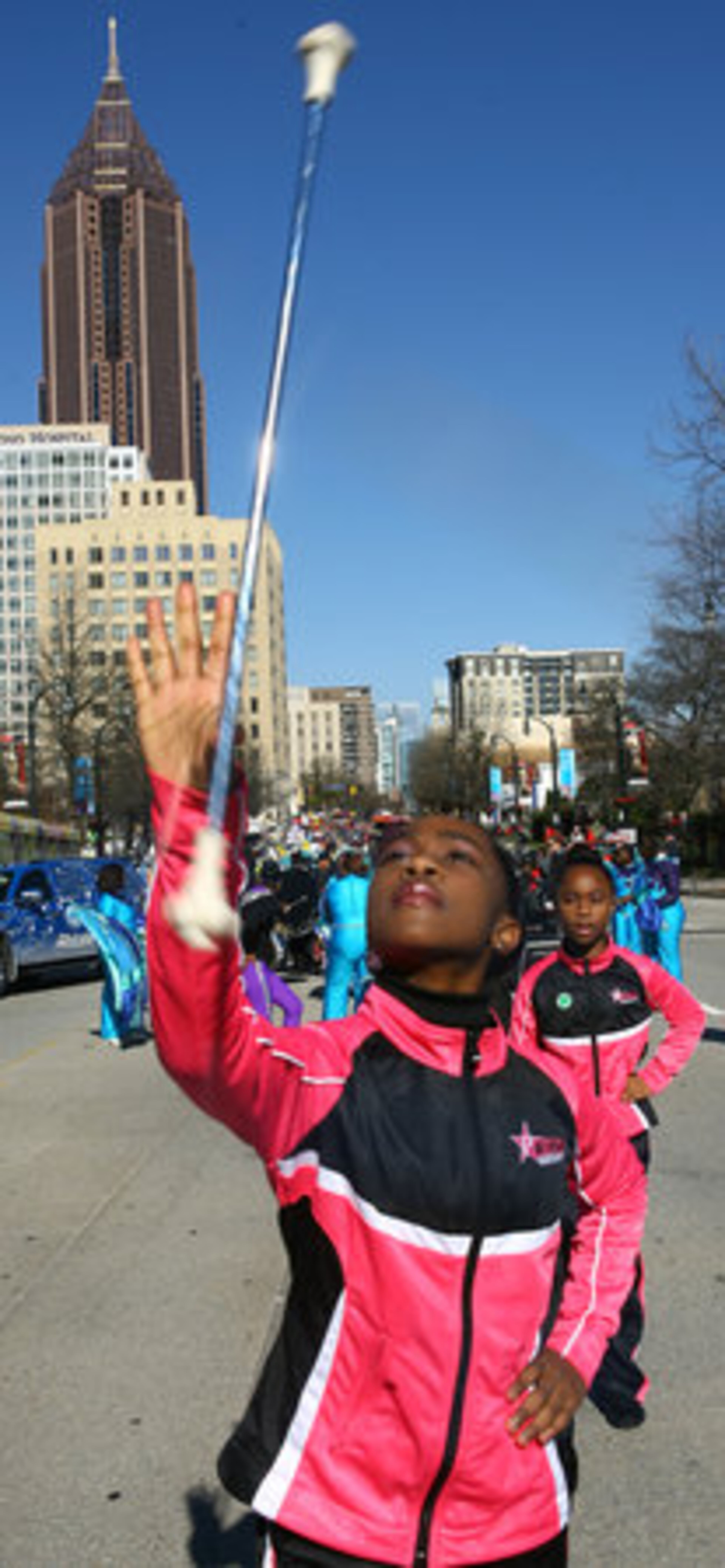 Savannah Peterson, 11, of College Park demonstrates her prowess with the baton as her younger sister, Nyla Peterson, 10, watches from behind as they prepare to march with the Precision Auxiliary Corp Twirlers of Atlanta.