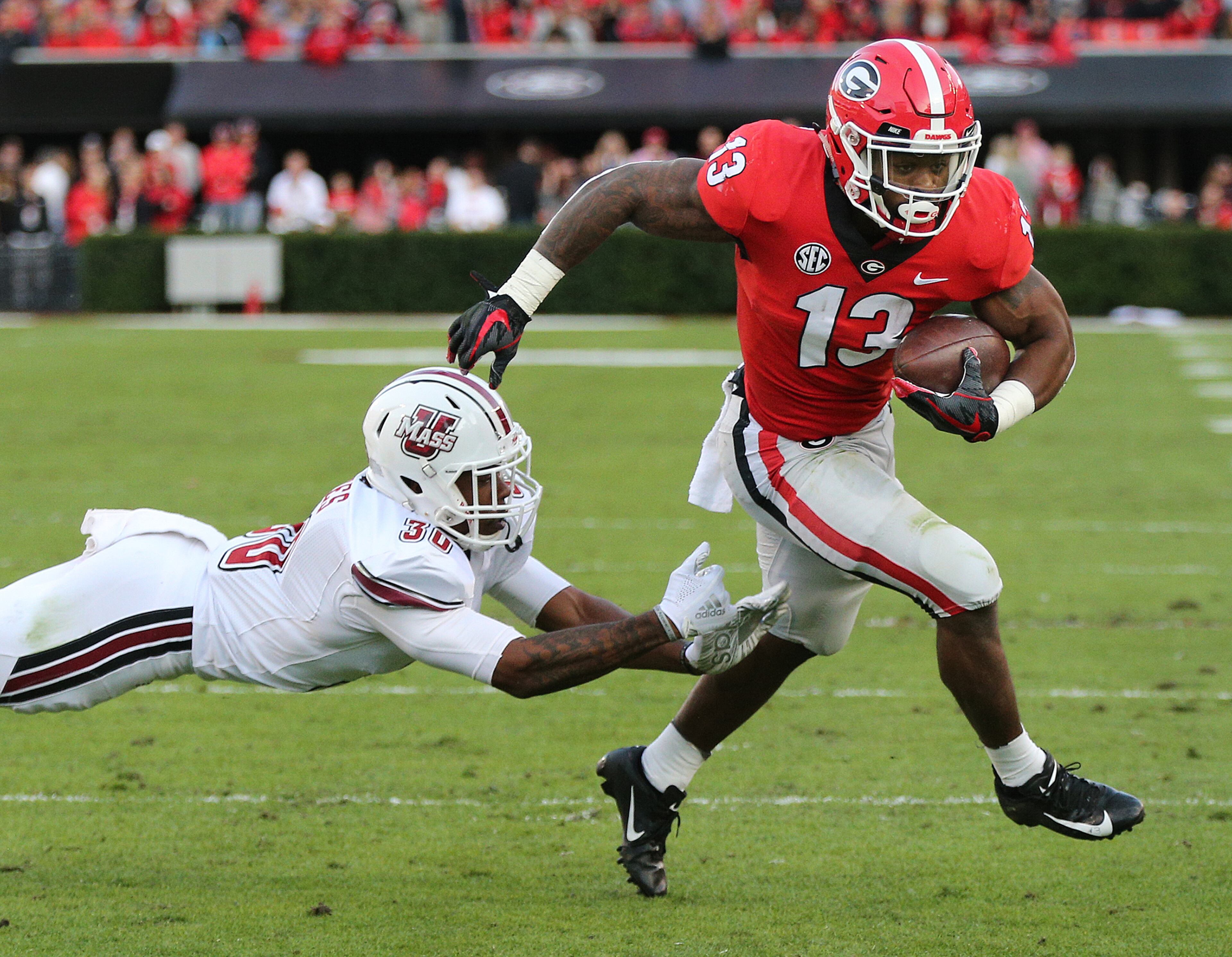 Nov 17, 2018 Athens: Georgia tailback Elijah Holyfield breaks away from Massachusetts safety Tyler Hayes for a touchdown and a 14-0 lead during the first quarter in a NCAA college football game on Saturday, Nov. 17, 2018, in Athens. Curtis Compton/ccompton@ajc.com
