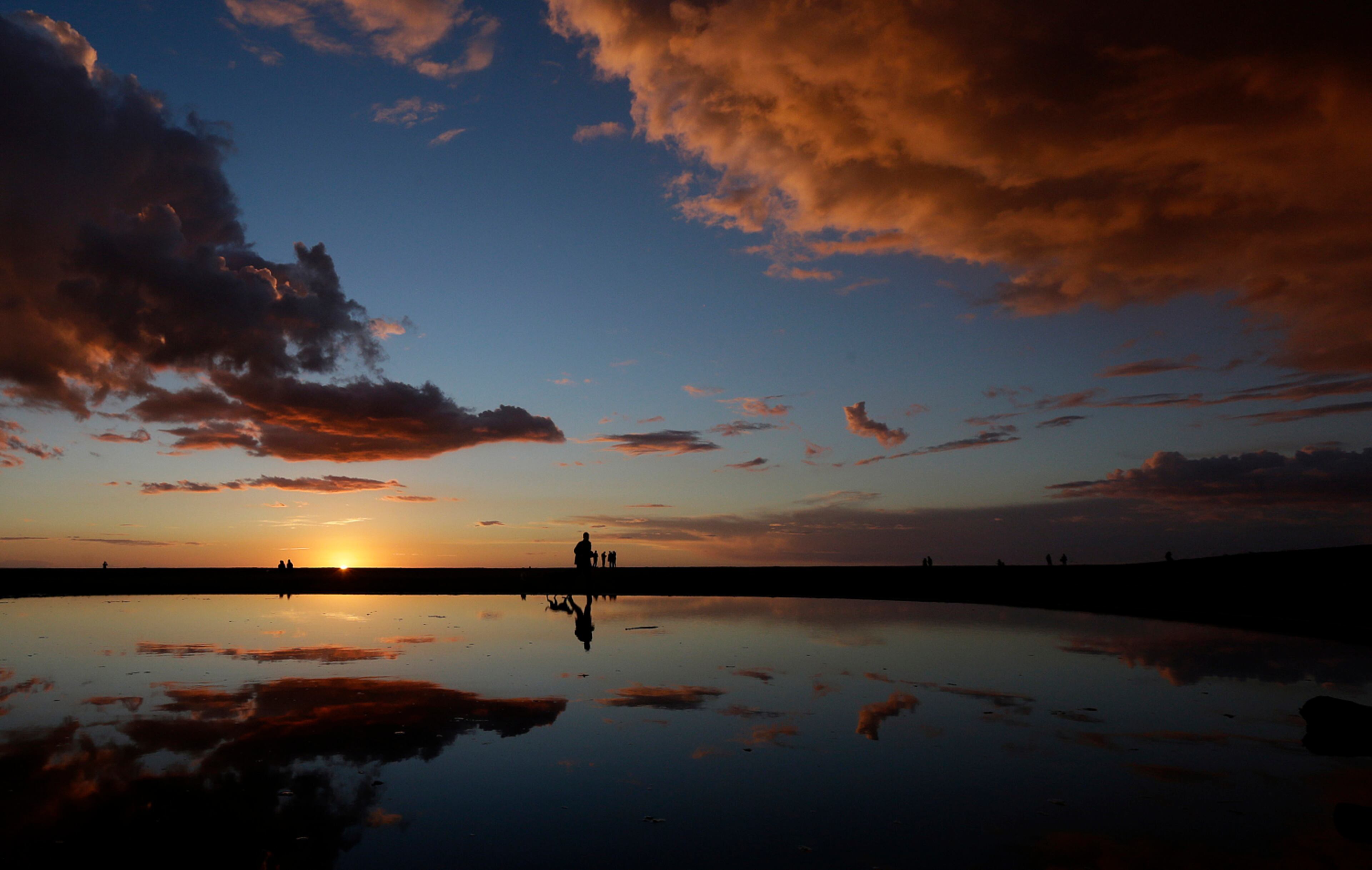 SUNSET WALK--A man walks his dogs past a puddle as the sun sets at Ocean Beach in San Francisco, Saturday, Feb. 28, 2015. (AP Photo/Jeff Chiu)