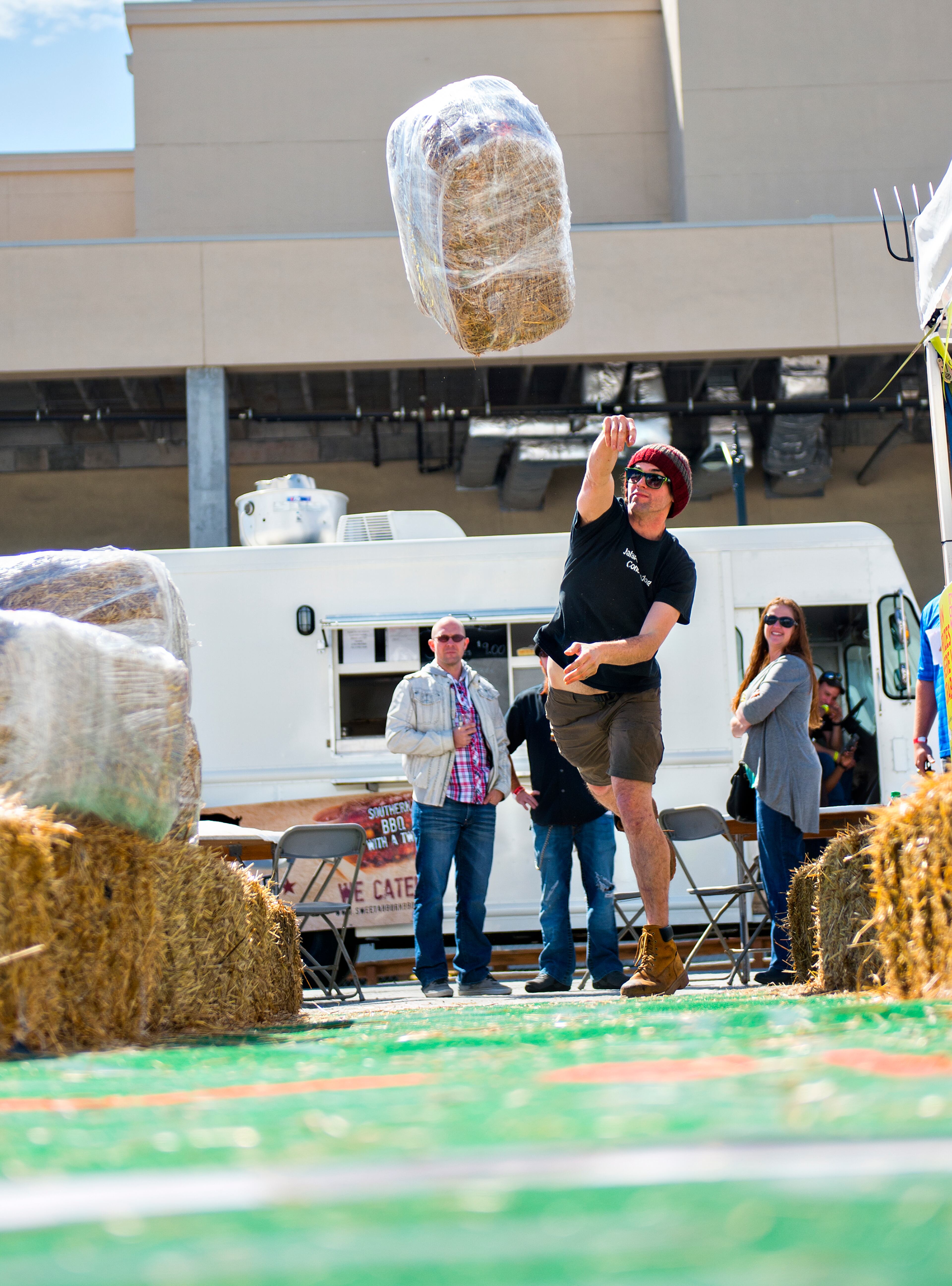 Landis Zehrung (center) heaves a bale of hay into the air during the sixth annual Beer Carnival at Atlantic Station in downtown Atlanta on Saturday, March 21, 2015. Over 4,000 people attended the event which featured beer from breweries all over the country as well as carnival styled games, food, music and more. JONATHAN PHILLIPS / SPECIAL
