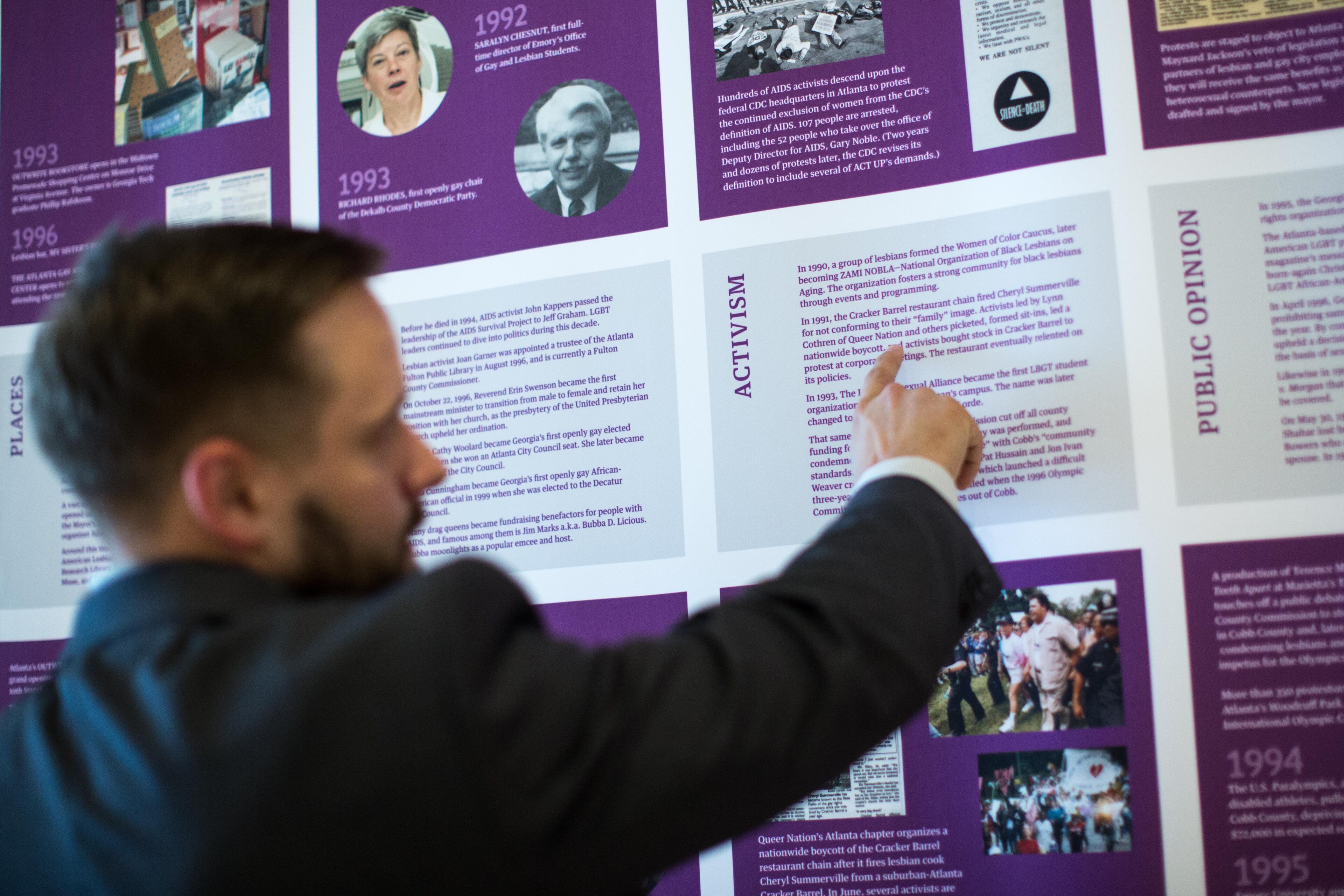 Ryan Roemerman, interim executive director for the LGBT Institute, points to an article on display at the "Forward Together: A Look at Atlanta's LGBT History Since Stonewall" exhibit at the Center for Civil and Human Rights, Tuesday, Sept. 1, 2015, in Atlanta. Leaders of an Atlanta museum want the space focused on modern and historic civil rights to contribute to a national push to ensure LGBT rights, particularly in southern states. (AP Photo/Branden Camp)
