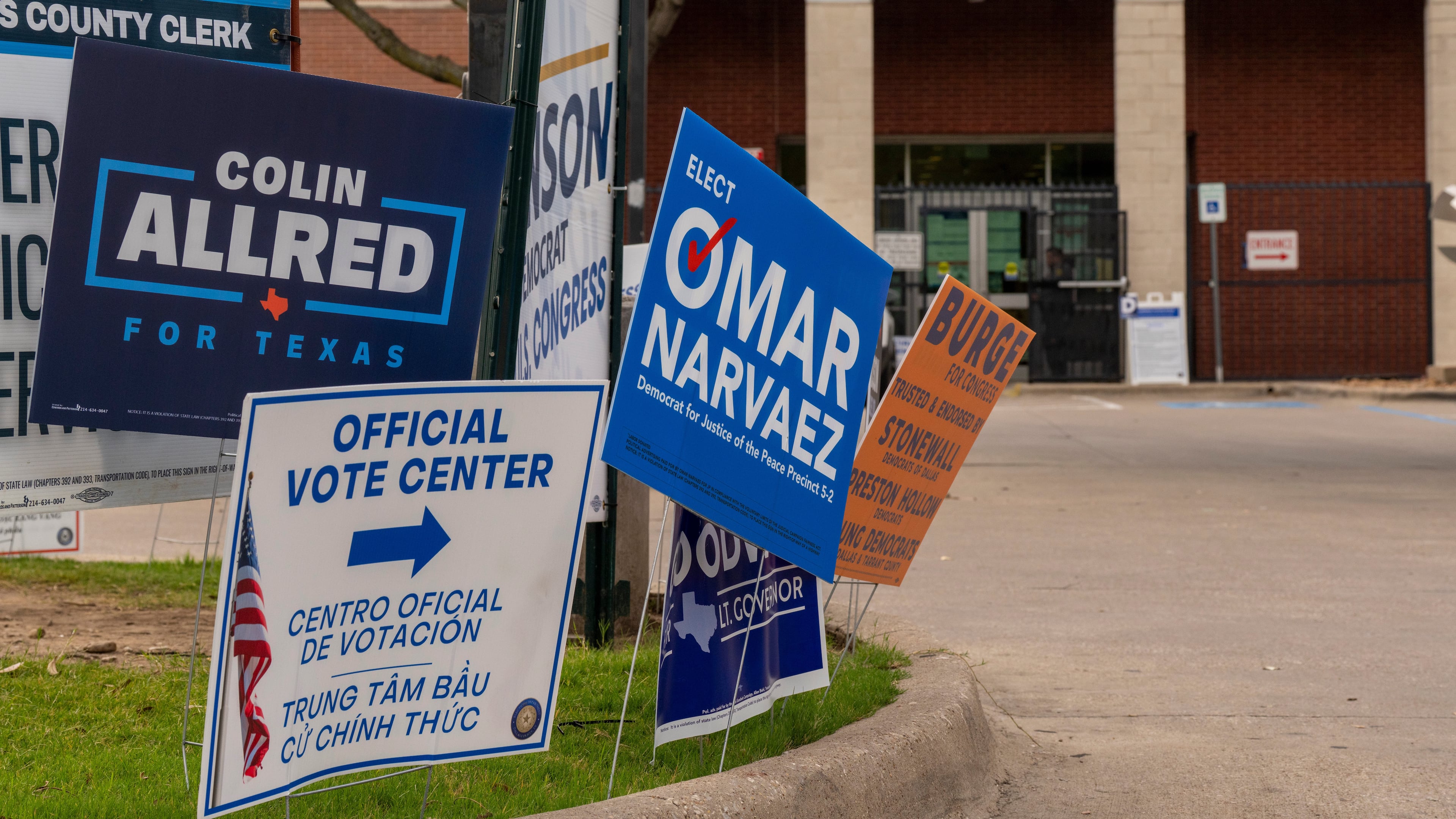 Candidate signs line the entrance to the Oak Lawn Branch Library polling location as voters cast ballots in local and primary runoff elections Tuesday, May 26, 2026, in Dallas. (AP Photo/Gabriela Passos)