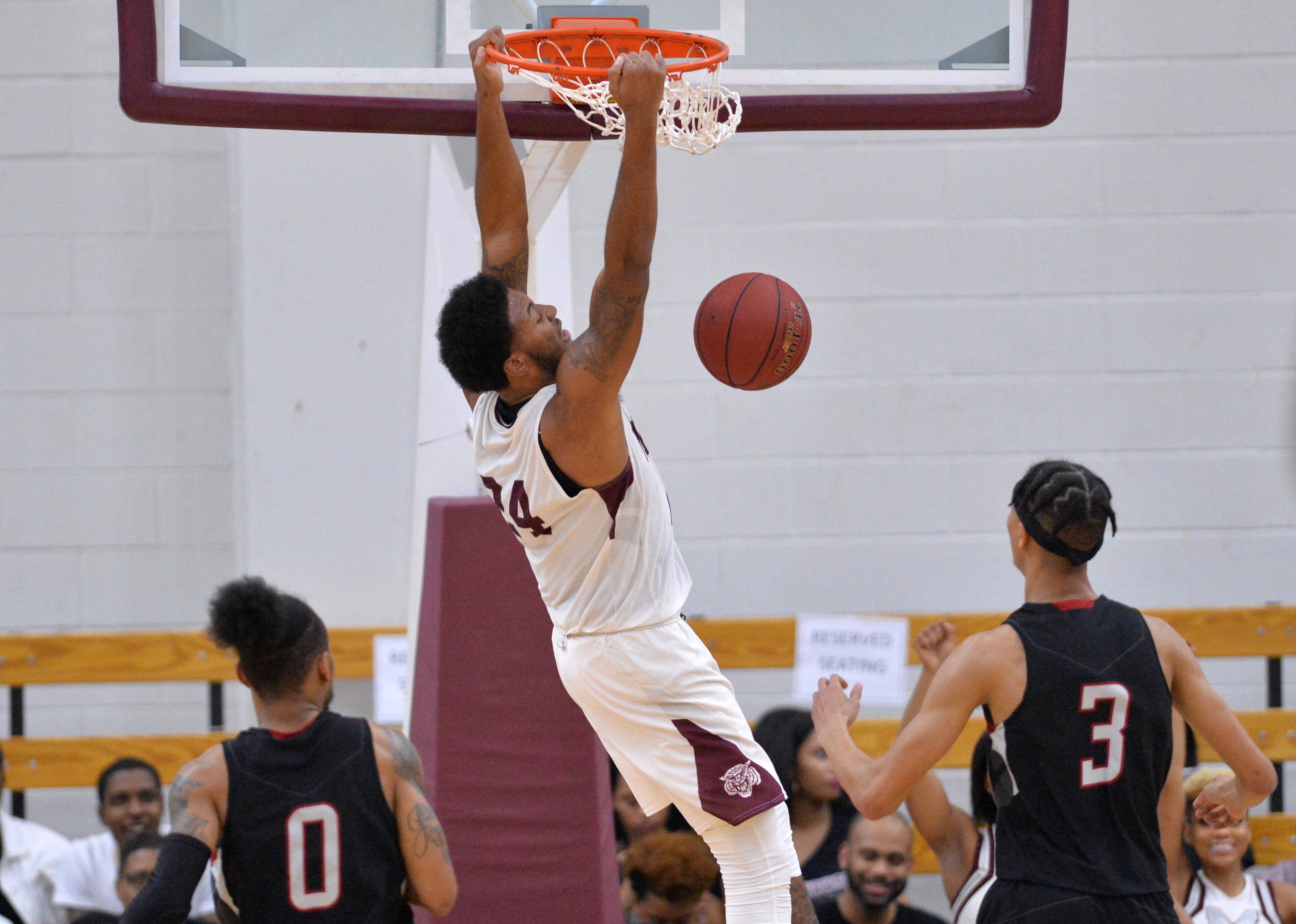 Morehouse's Omar Alston (24) hangs on the basket after dunking. HYOSUB SHIN / HSHIN@AJC.COM