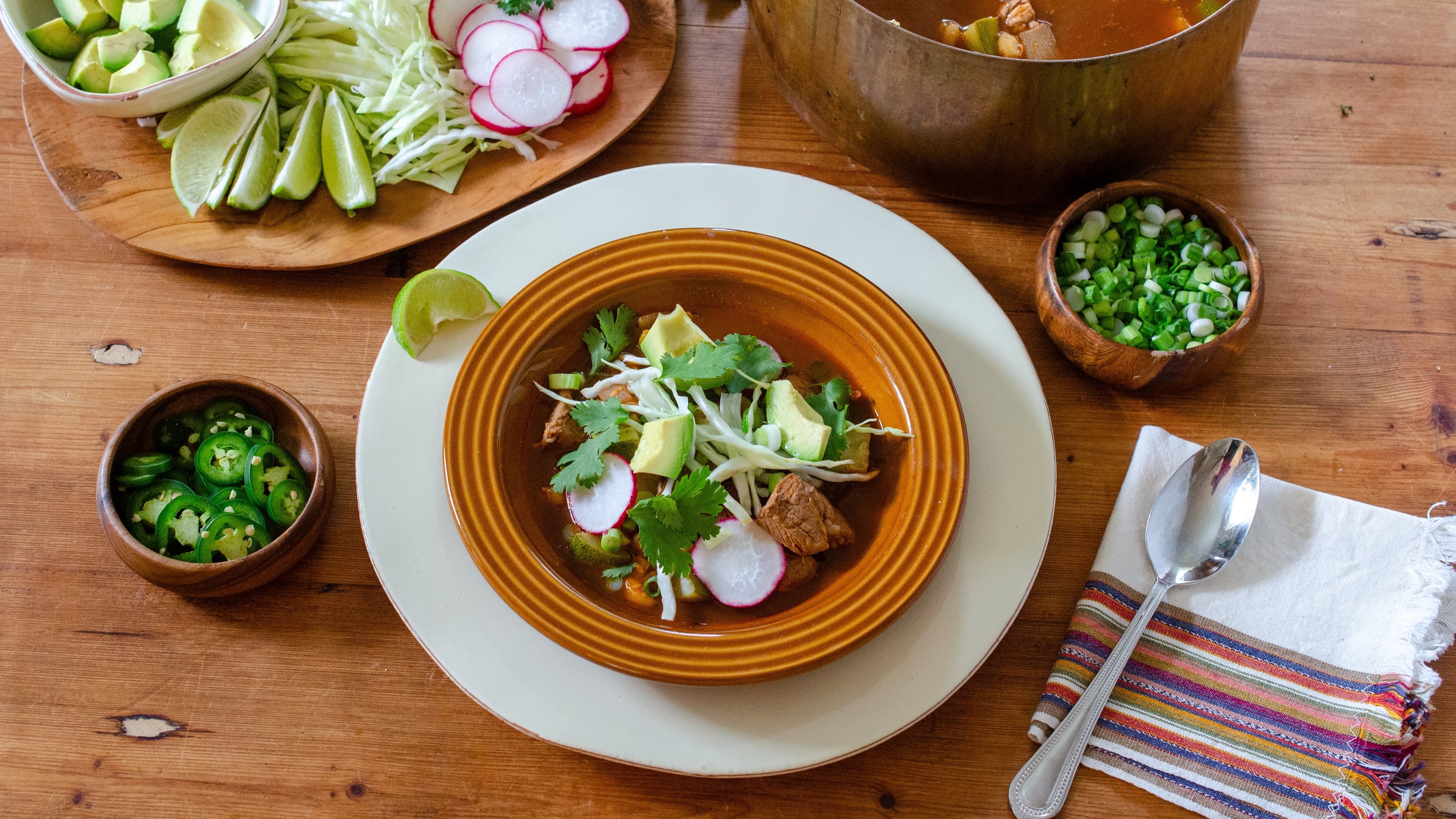 Zucchini adds more vegetables to this Quick Pork Tenderloin Pozole Rojo. It's served with the traditional toppings. (Virginia Willis for the AJC)
