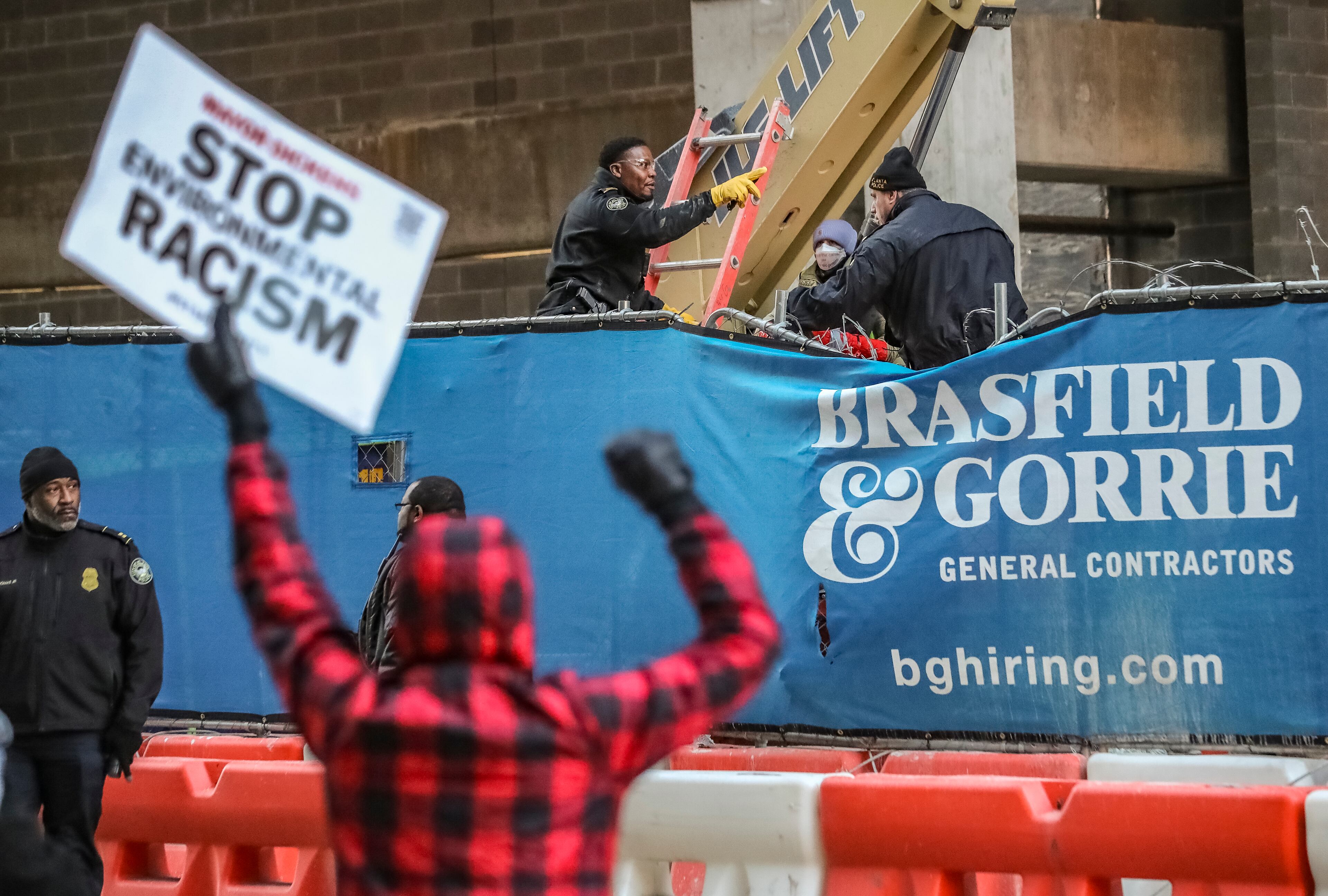 Two people locked themselves to construction equipment in Midtown to protest Atlanta’s planned public safety training center, causing a street to close amid the Monday morning commute, Jan. 29, 2024. The activists used reinforced bindings to lock their arms around the equipment at a Brasfield & Gorrie work site at 12th and Juniper streets. One person was locked to a construction elevator and the other to a boom. Both were released by 10:15 a.m. Juniper Street was closed to traffic for hours Monday morning before reopening around 11:30 a.m. SWAT team members were also at the scene for assistance in cutting the activists free. Brasfield & Gorrie is one of the contractors hired to build the training facility at the site of the old Atlanta Prison Farm in the south DeKalb County woods. Those opposed to the facility say its construction will damage the South River Forest and contribute to what they say is the militarization of the police department. (John Spink / John.Spink@ajc.com)