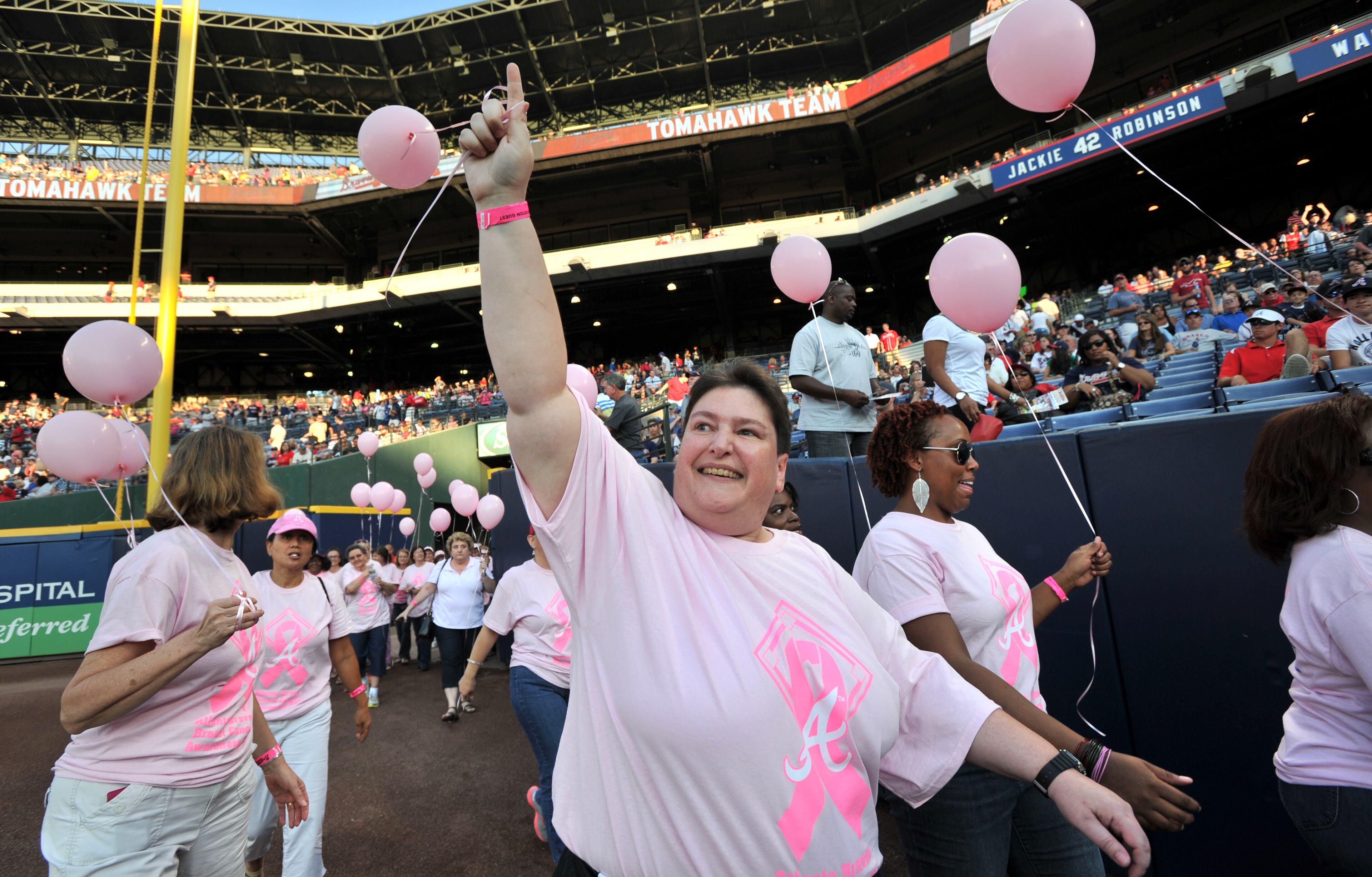 Kristen Lordo (center) waves as she walks with About 300 survivors and their families marched on field during "A Walk in the Park," a pregame ceremony before Atlanta Braves game against the San Diego Padres at Turner Field on Saturday, September 14, 2013. This season, the Braves, WellStar Health System, Kroger and the American Cancer Society Making Strides Against Breast Cancer teamed up for the 7th annual Braves Breast Cancer Awareness Day. The day-long celebration of survivorship honors those who have courageously battled breast cancer, and raised awareness and funds to support research, education and advocacy for cancer patients and their families throughout metro Atlanta.