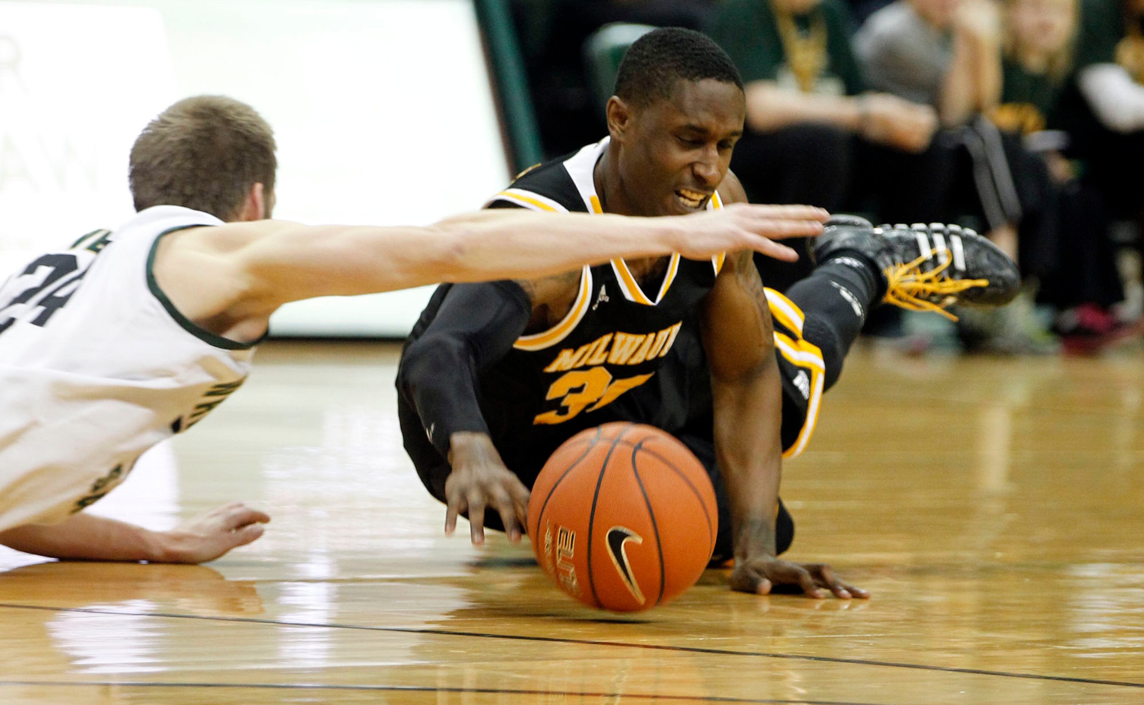 Wright State's Matt Vest crashed into Milwaukee's JeVon Lyle for this loose ball as the Raiders hosted the Panthers for the Horizon League Championship. TY GREENLEES / STAFF