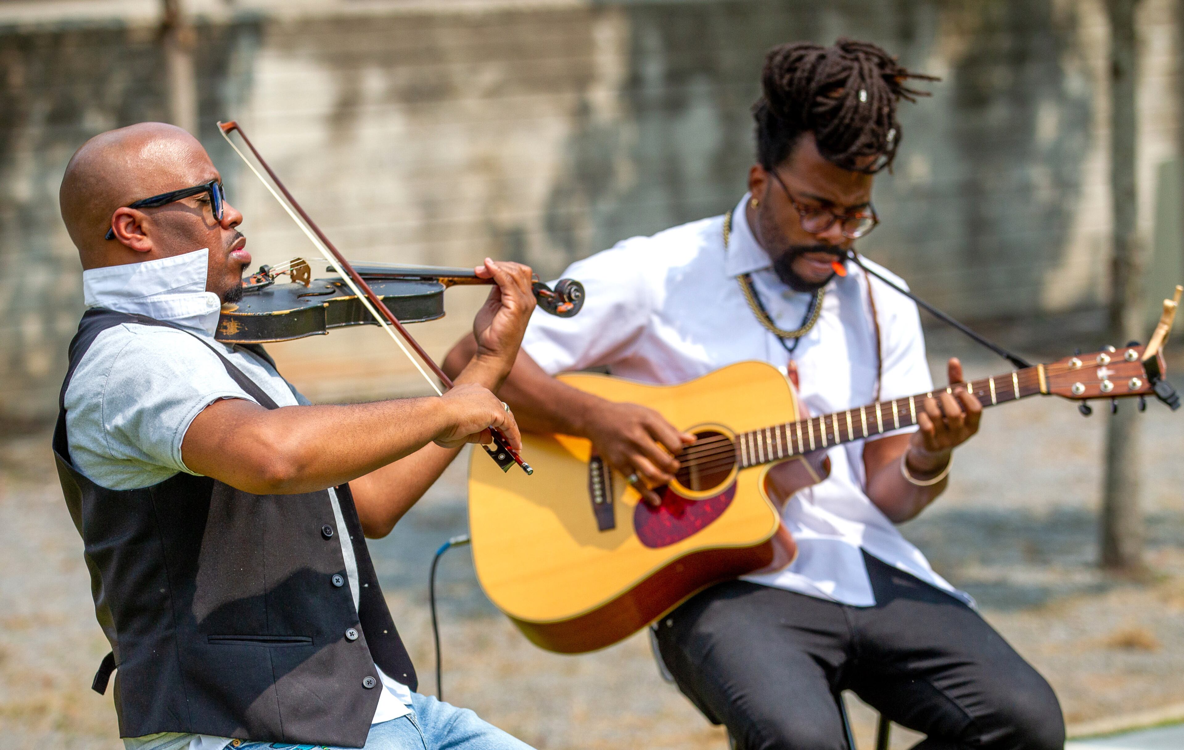 Kevin Grayson (left) and Jeremiah Turner play music during the unveiling ceremony of artist Ellex Swavoni's sculpture "What Sonia Said" in Decatur on Sunday, September 12, 2021. STEVE SCHAEFER FOR THE ATLANTA JOURNAL-CONSTITUTION