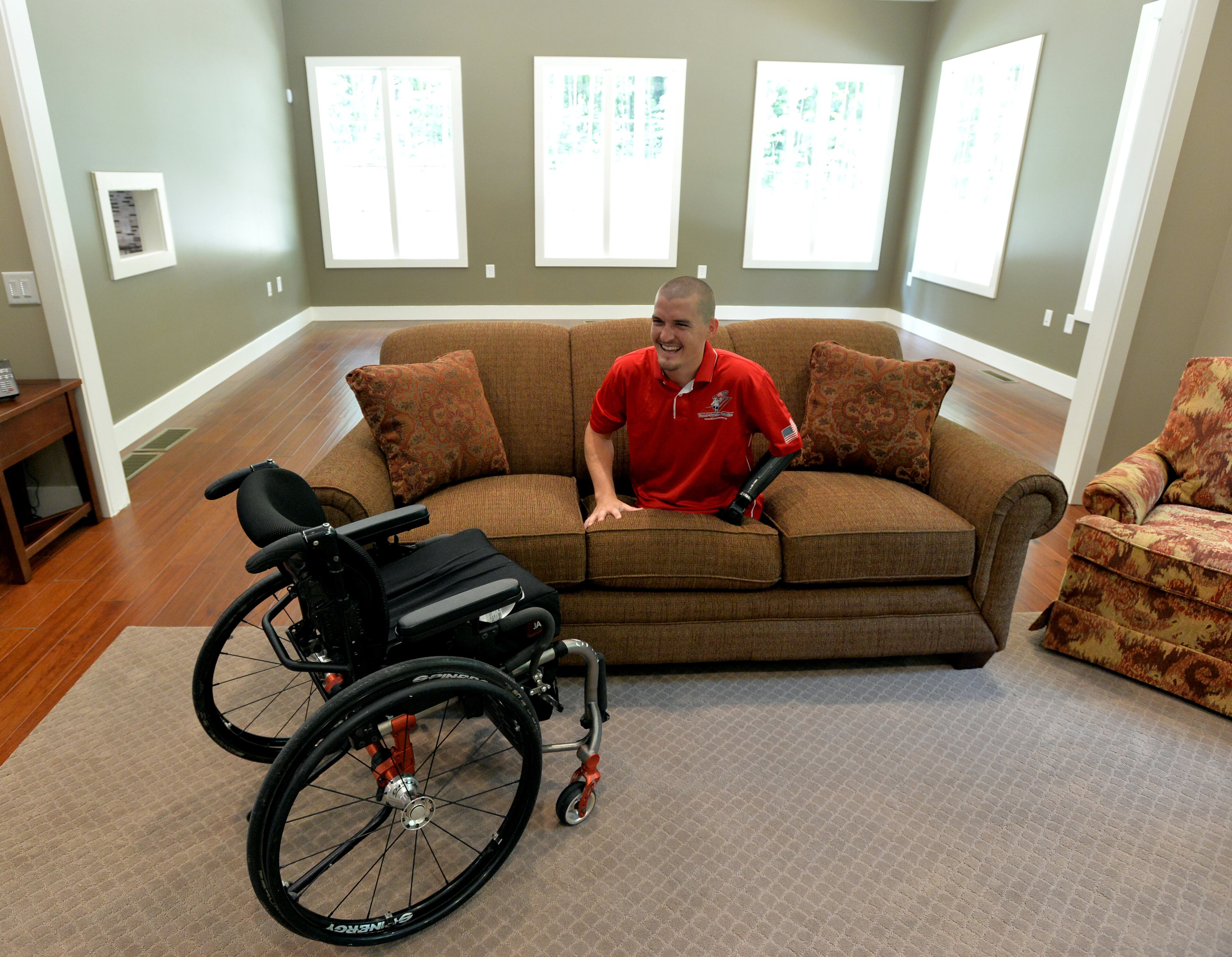 Marine Corporal Todd Love checks out the sofa in his new home Monday June 30, 2014. Love lost both legs and his left arm to an IED blast in 2010 while on patrol in Afghanistan. Home Depot and other corporate sponsors, in conjunction with the Stephen Siller Tunnel to Towers Foundation and the Gary Sinise Foundation, built the home as part of the Building for America's Bravest program. The 3700 feet 4 bed 3 bath "smart home" features an open floor plan, automatic toilets, oversize shower with roll in access, motorized doors, drop down kitchen cabinets that make it easier for Love to reach stored items, a cook top that lowers and a complete security system just to name a few features that will make it easier for Love to take care of his needs. Most of the features of the home can be controlled from an ipad. BRANT SANDERLIN /BSANDERLIN@AJC.COM .