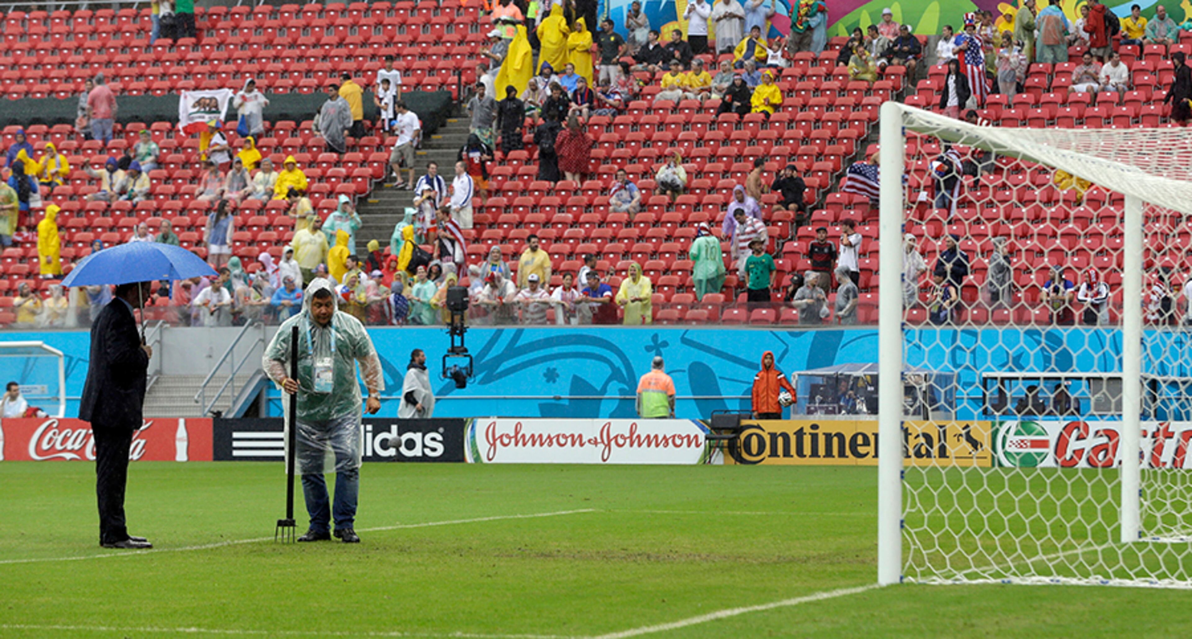 A FIFA official and grounds worker inspect the pitch after heavy rain before the group G World Cup soccer match between the United States and Germany at the Arena Pernambuco in Recife, Brazil, Thursday, June 26, 2014.