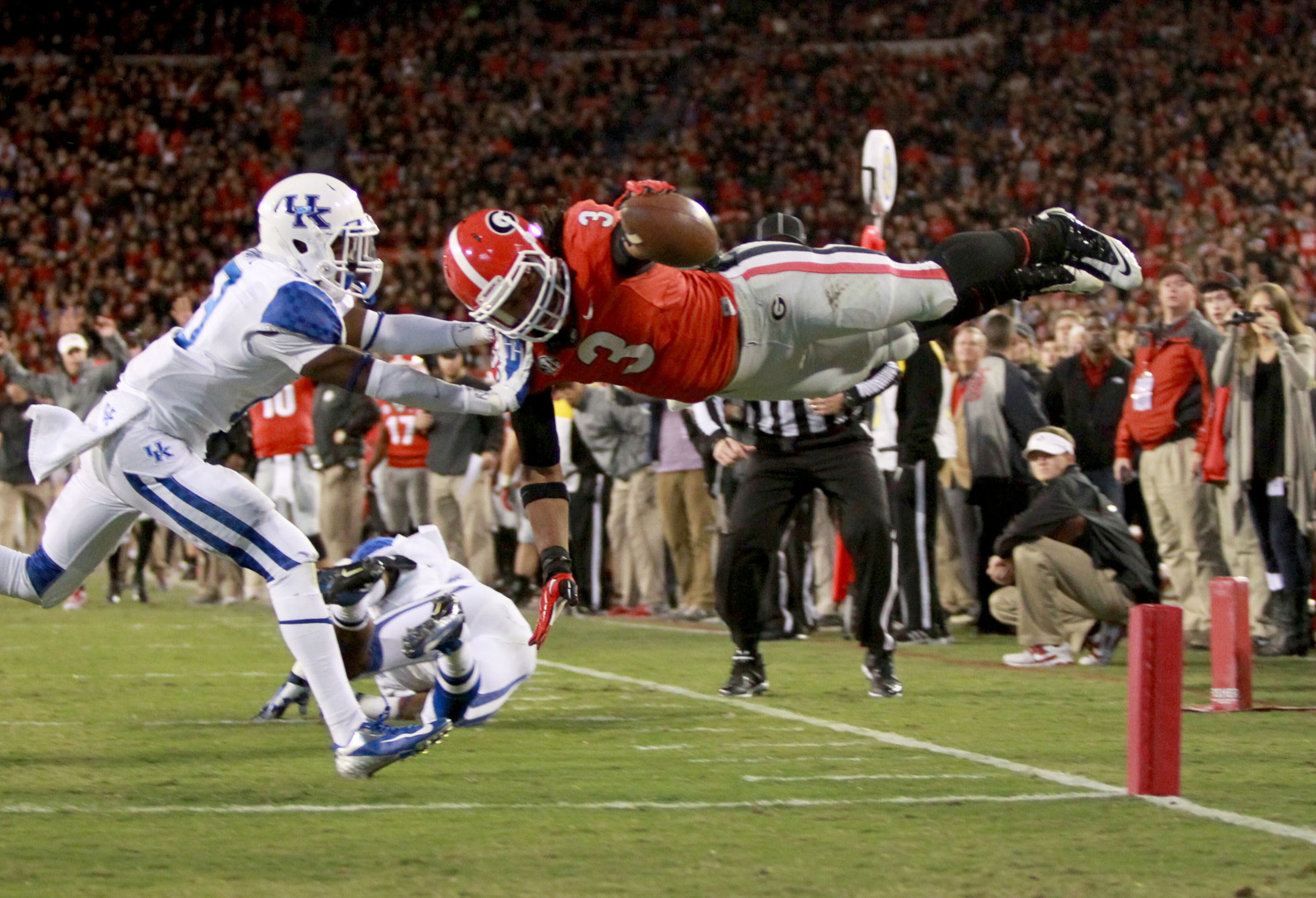 Todd Gurley dives for a 16-yard touchdown over the defense of Kentucky cornerback Jaleel Hytchye (left) and safety Ashely Lowery, Nov. 23, 2013. JASON GETZ/AJC