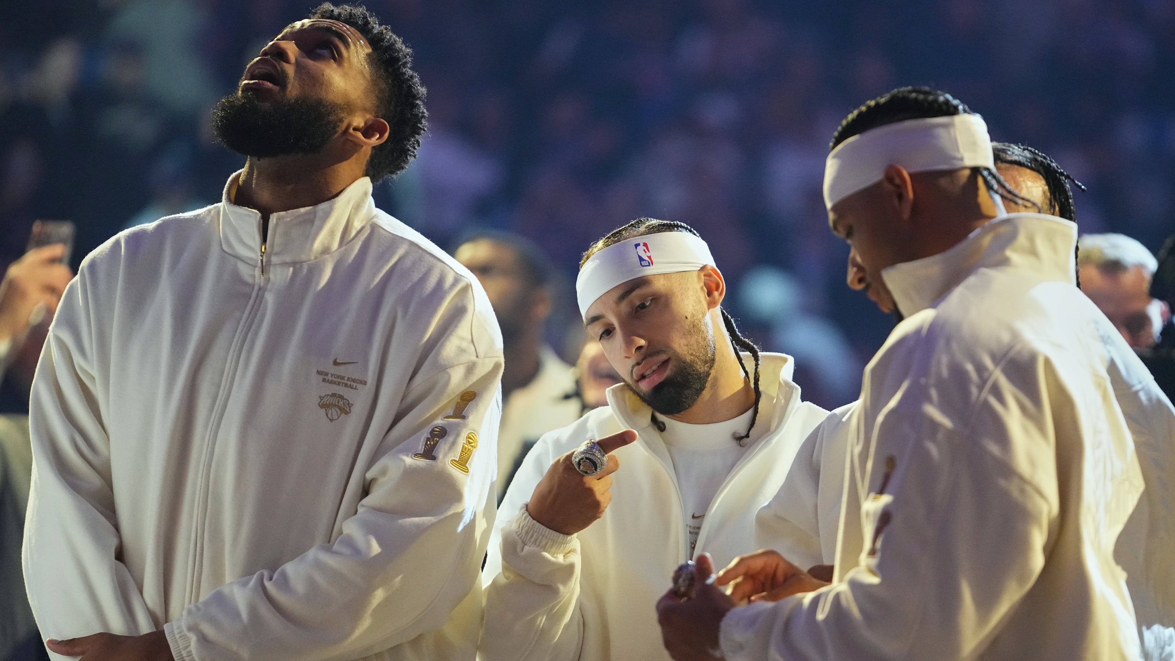 New York Knicks guard Jose Alvarado, center, looks at his 2025-26 World Champions ring alongside teammates center Karl-Anthony Towns, left, and guard Josh Hart before an NBA basketball game against the Philadelphia 76ers Tuesday, Oct. 20, 2026, in New York. (AP Photo/Frank Franklin II)