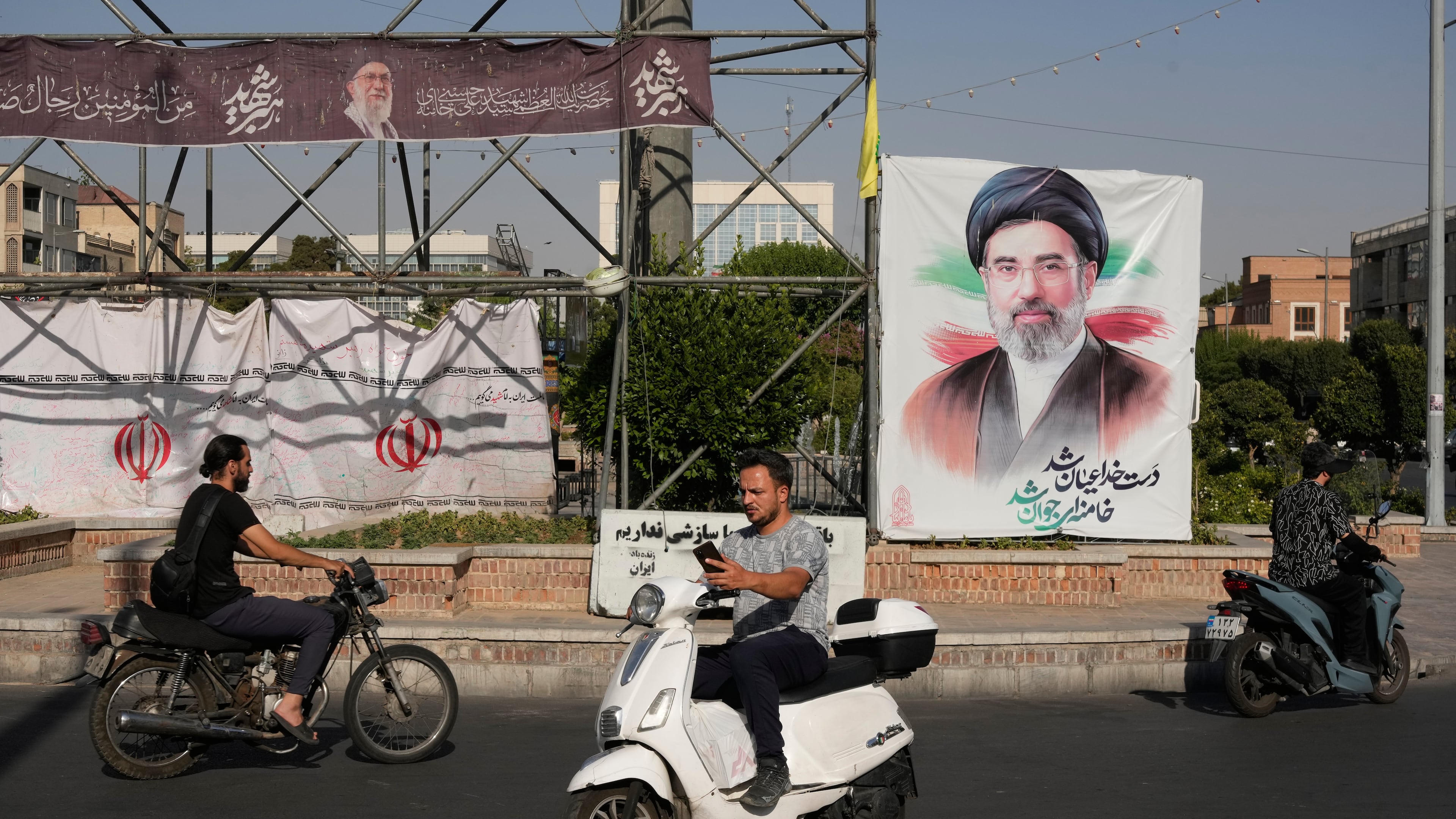 Motorbikes drive past a banner showing a portrait of the Iranian Supreme Leader Ayatollah Mojtaba Khamenei in downtown Tehran, Iran, Monday, June 29, 2026. (AP Photo/Vahid Salemi)