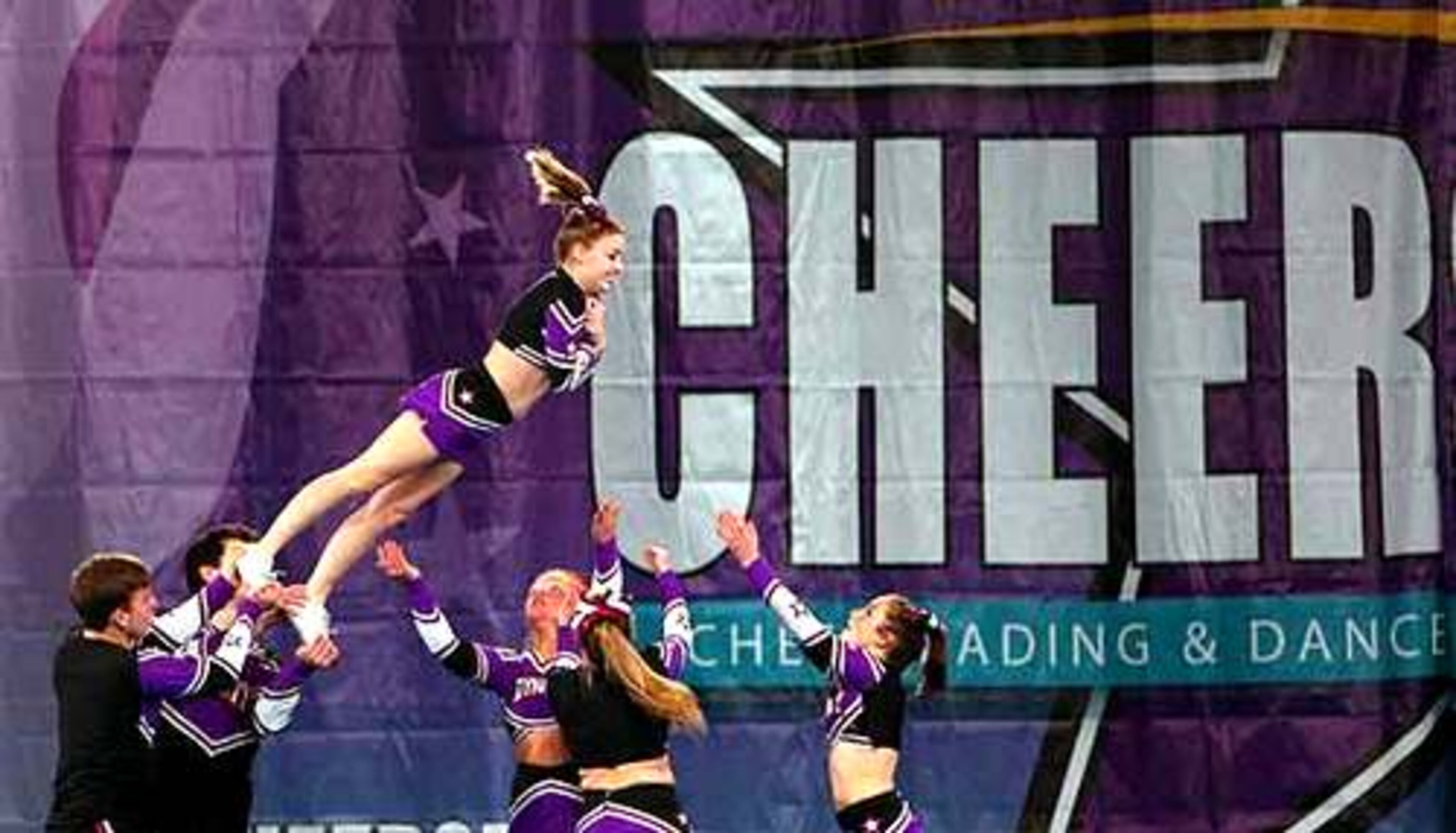 Courtney O'Hara falls in the waiting arms of her teammates. Their team, Cheer Dynasty, is from Manassas, Va.