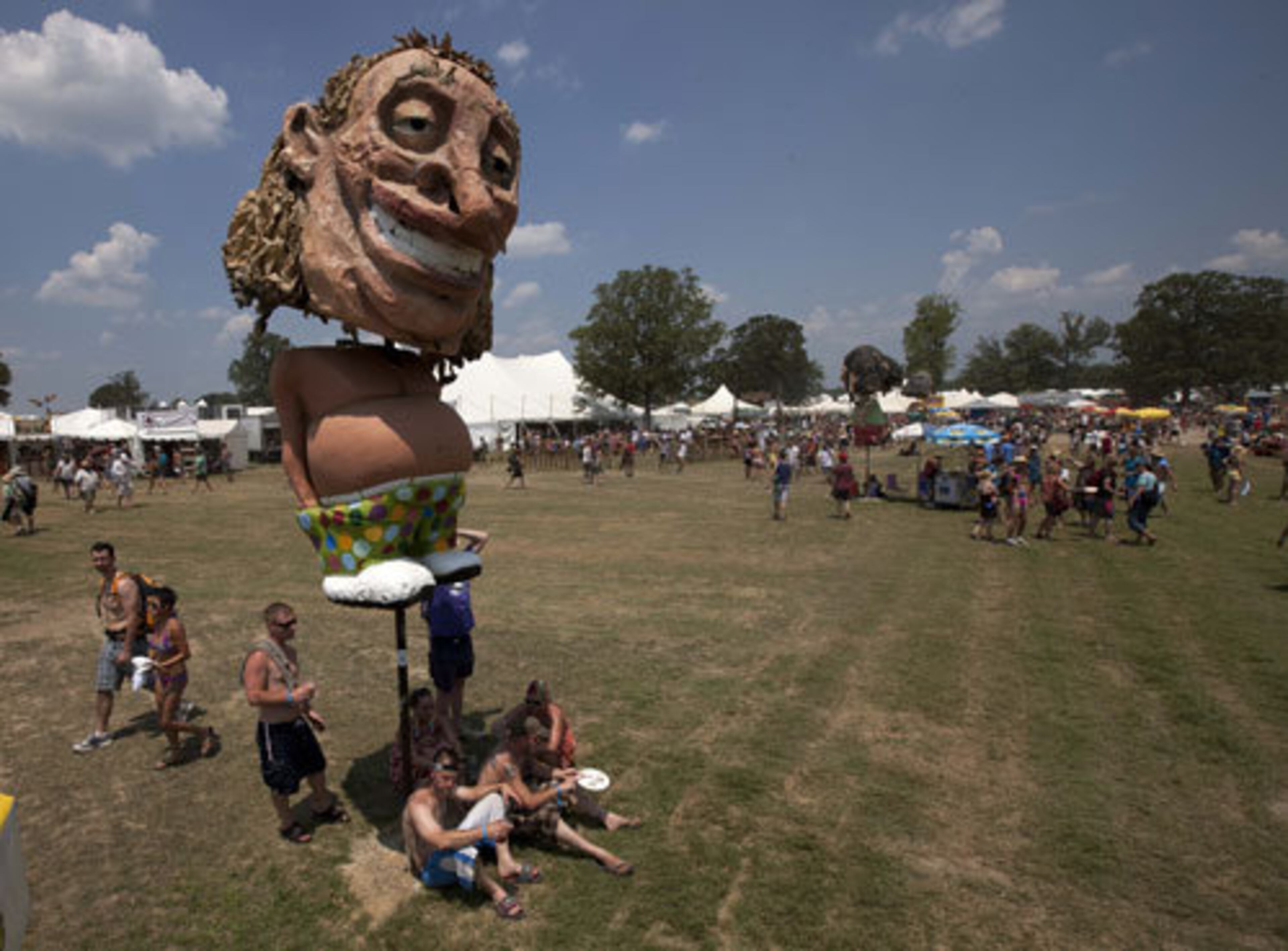 Music lovers gather beneath a sculpture for shade.