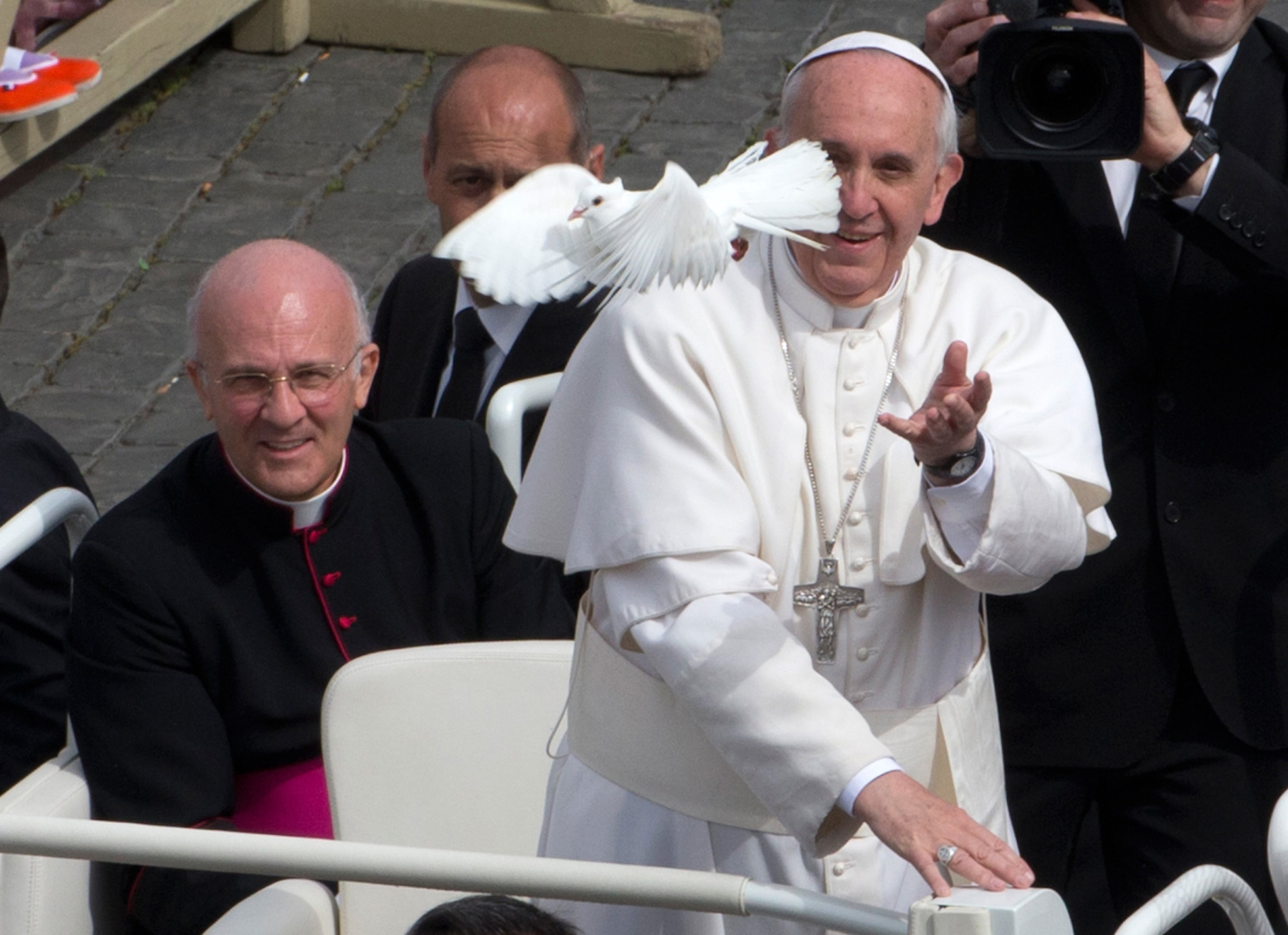 Pope Francis frees a dove during his weekly general audience in St. Peter Square at the Vatican, Wednesday, May 15, 2013. As Francis toured the square in his open-topped popemobile at his Wednesday audience with the public, someone at the edge of the crowd thrust a white bird cage at him. Looking puzzled, his security detail took the cage, containing a pair of white doves, and handed it to Francis. Without hesitation, the pope opened the cage door, thrust a hand inside and extracted one dove, and with a flick of his hand, sent the bird flying over the square. (AP Photo/Alessandra Tarantino)