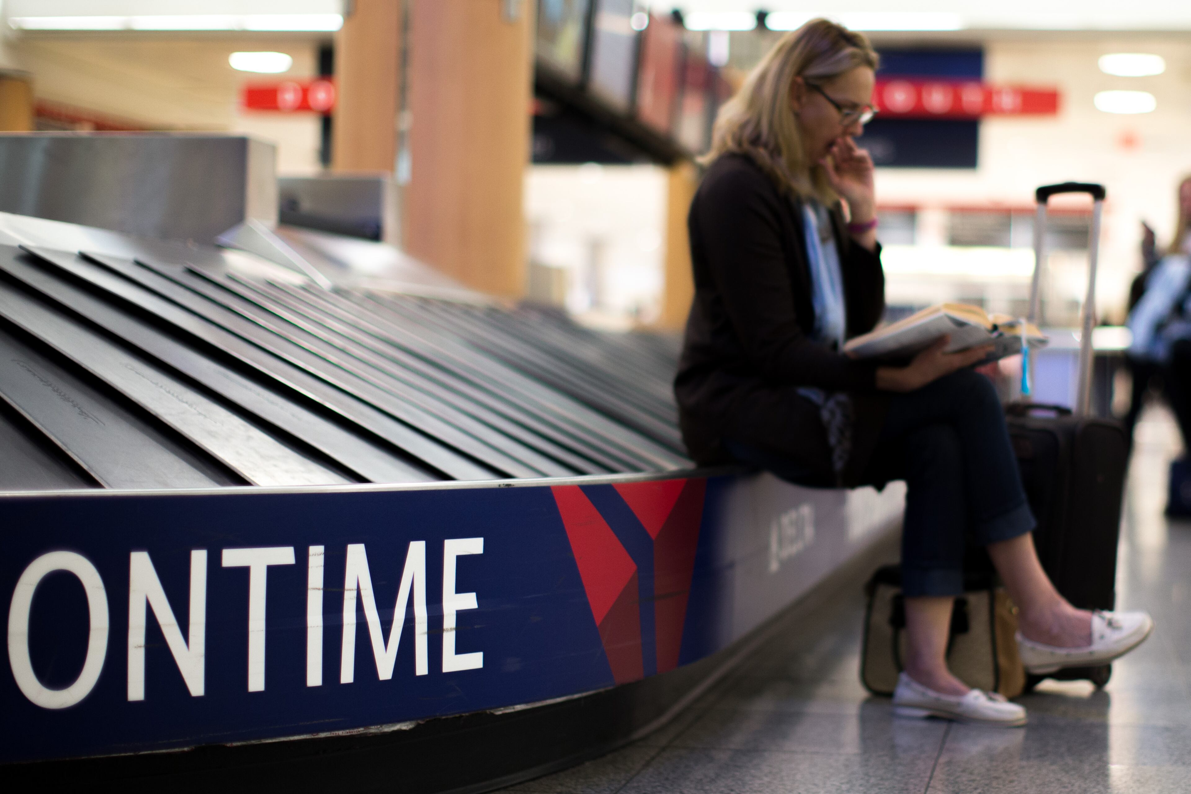 A woman sits on a Delta baggage carousel at Hartsfield-Jackson Atlanta International Airport, Friday, Jan. 6, 2017, in Atlanta. Delta canceled about 350 flights due to inclement weather. BRANDEN CAMP/SPECIAL