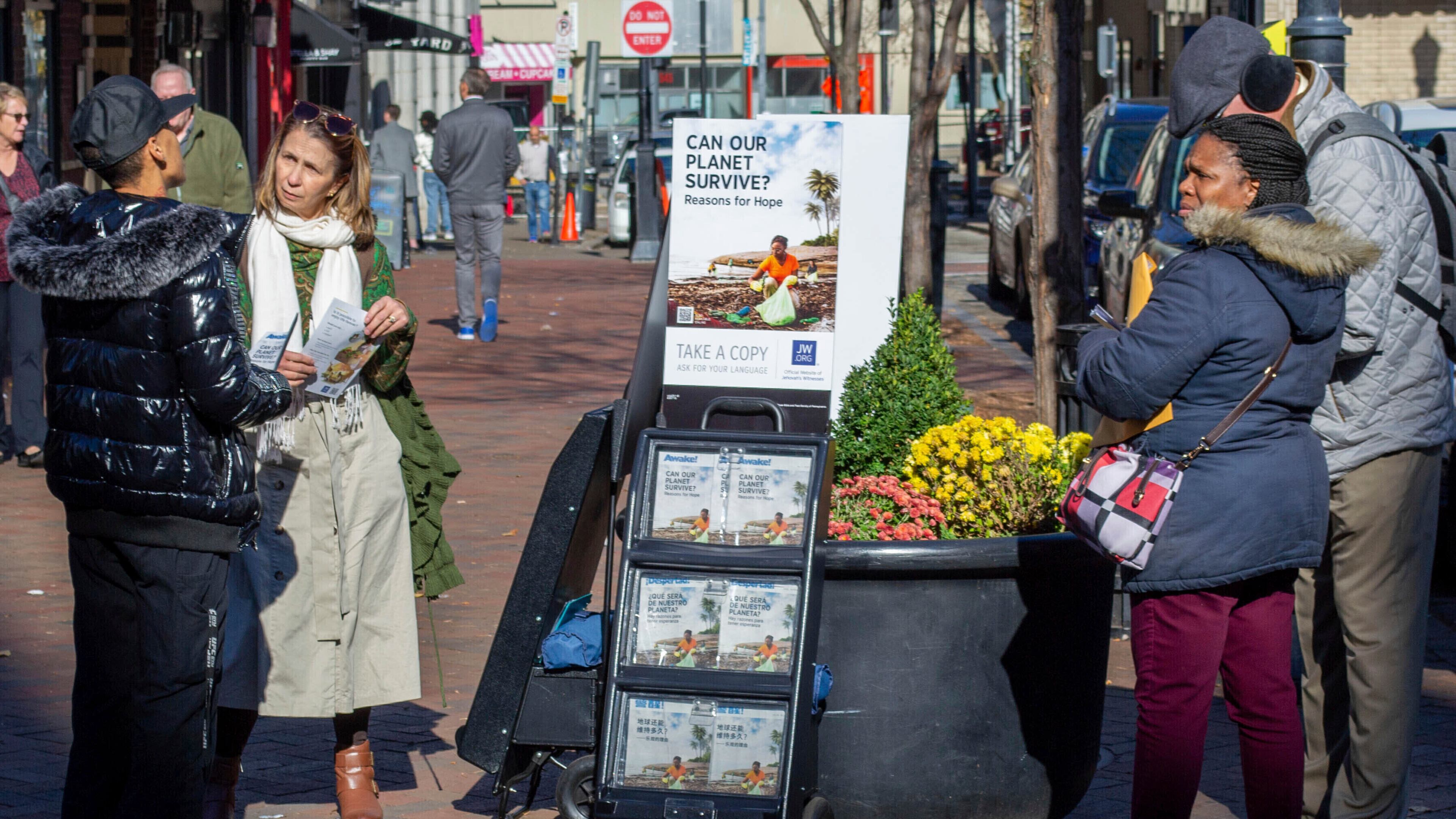 FILE - A woman shares Jehovah's Witnesses' literature with a passerby in downtown Pittsburgh on Monday, Nov. 13, 2023. (AP Photo/Peter Smith, File)