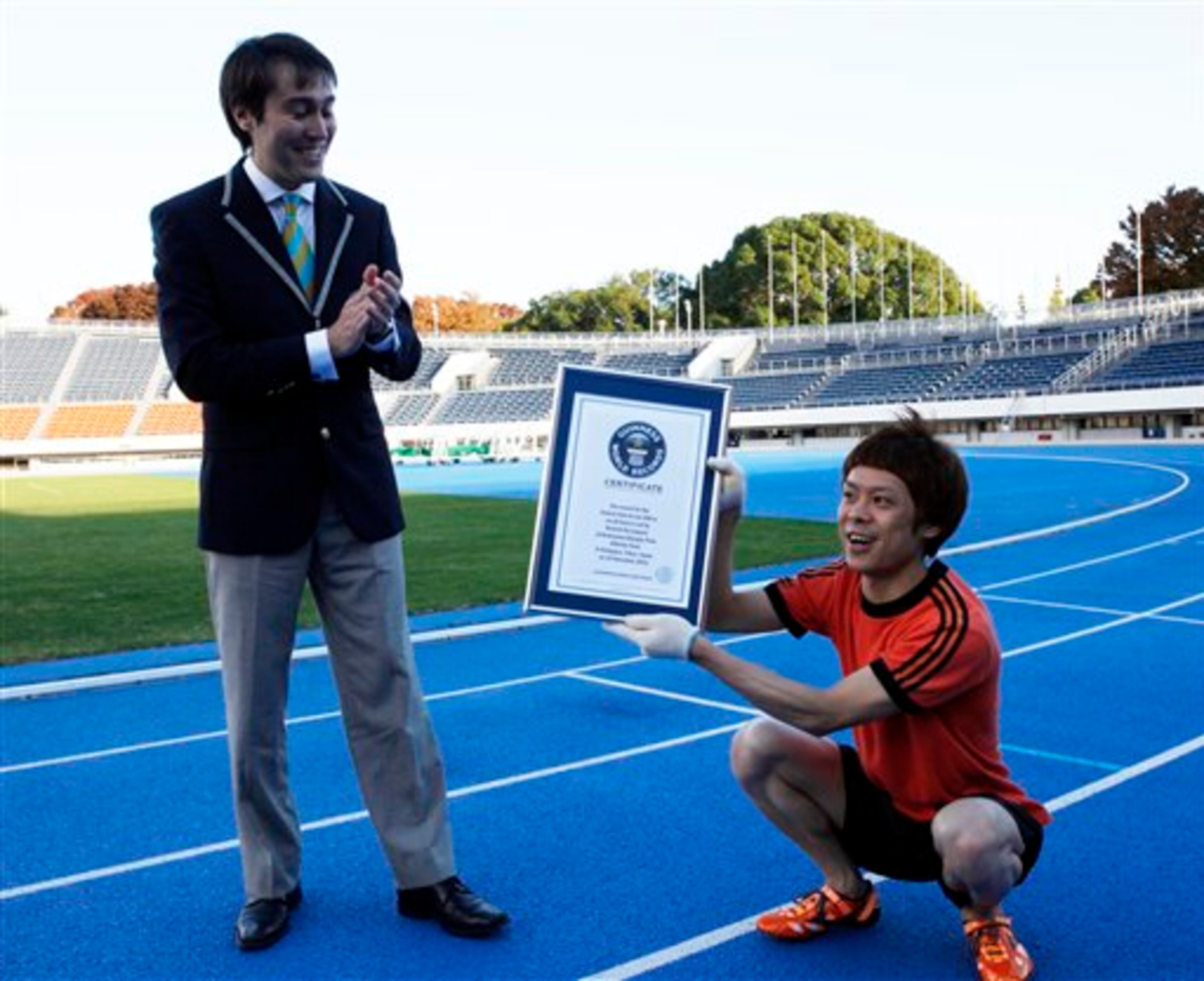 Kenichi Ito, right, receives a Certificate of the Guinness World Records from its official Adjudicator Carlos Martinez after setting the fastest time to run 100 meters on all fours at Komazawa Olympic Park Stadium in Tokyo Thursday, Nov. 15, 2012. Known as "Monkey Man," Ito, 30, who has trained the four-legged style walking and running for nine years in his daily life by studying primates' movements through books, video and visiting the zoo frequently, ran in 17.47 seconds, 1.11 seconds faster than the time he set in 2008. (AP Photo/Koji Sasahara)