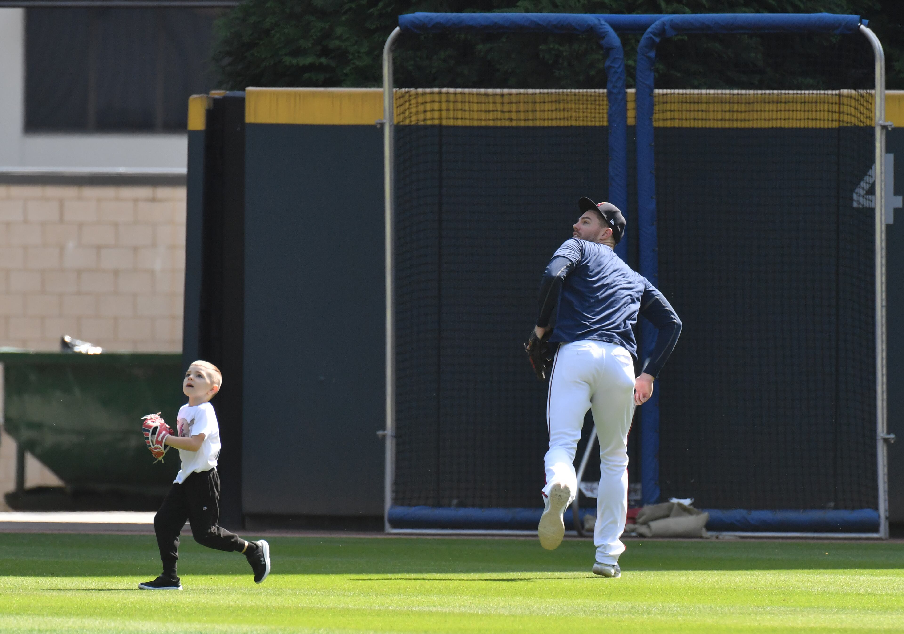 Braves first baseman Freddie Freeman fields fly balls alongside with his son, Charlie, in the outfield during a workout Thursday, Oct. 14, 2021, at Truist Park prior to the start of the 2021 NLCS on Saturday. (Hyosub Shin / Hyosub.Shin@ajc.com)