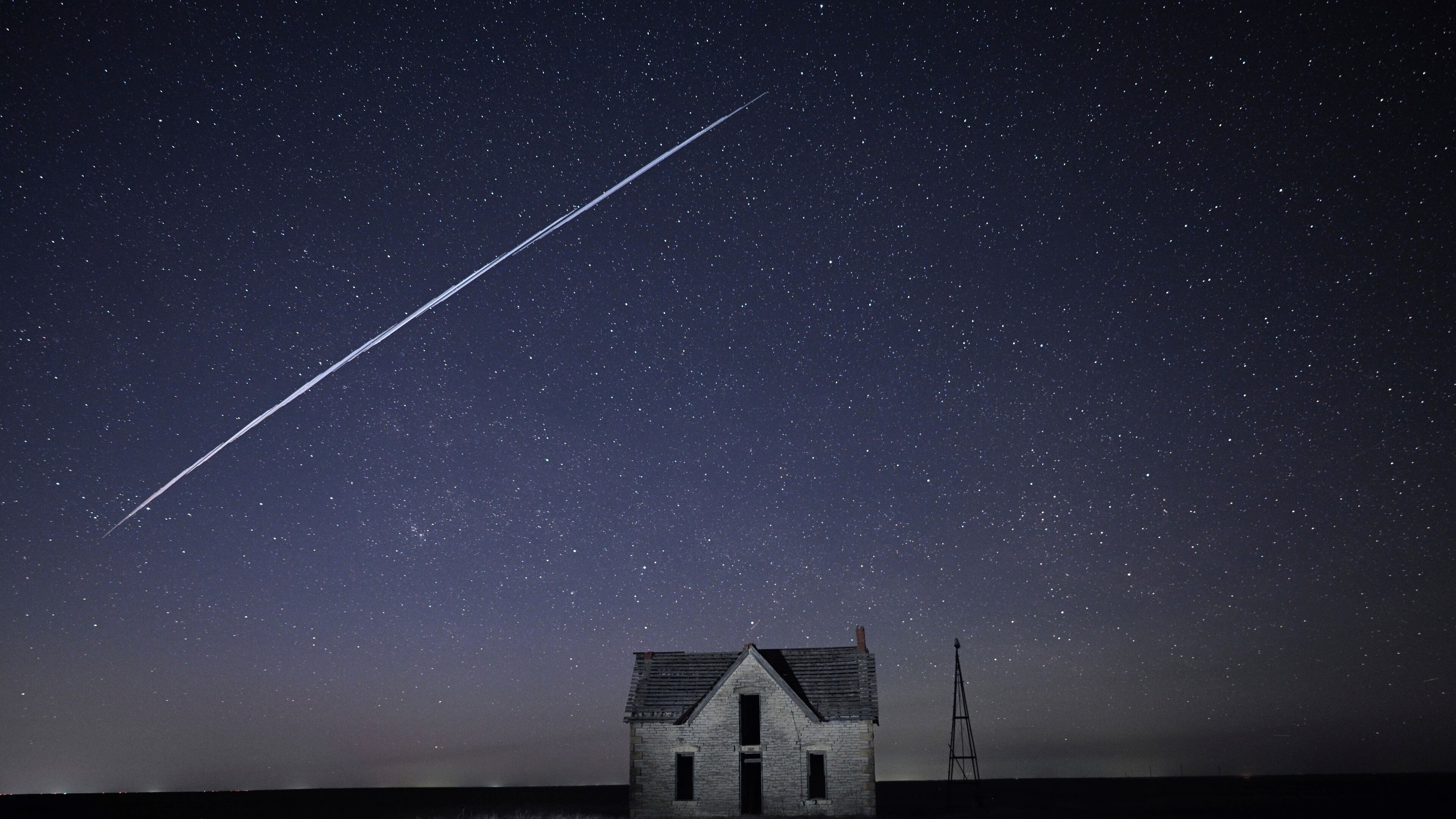 FILE - In this long exposure photo, a string of SpaceX StarLink satellites passes over an old stone house near Florence, Kan., on May 6, 2021. (AP Photo/Reed Hoffmann, File)