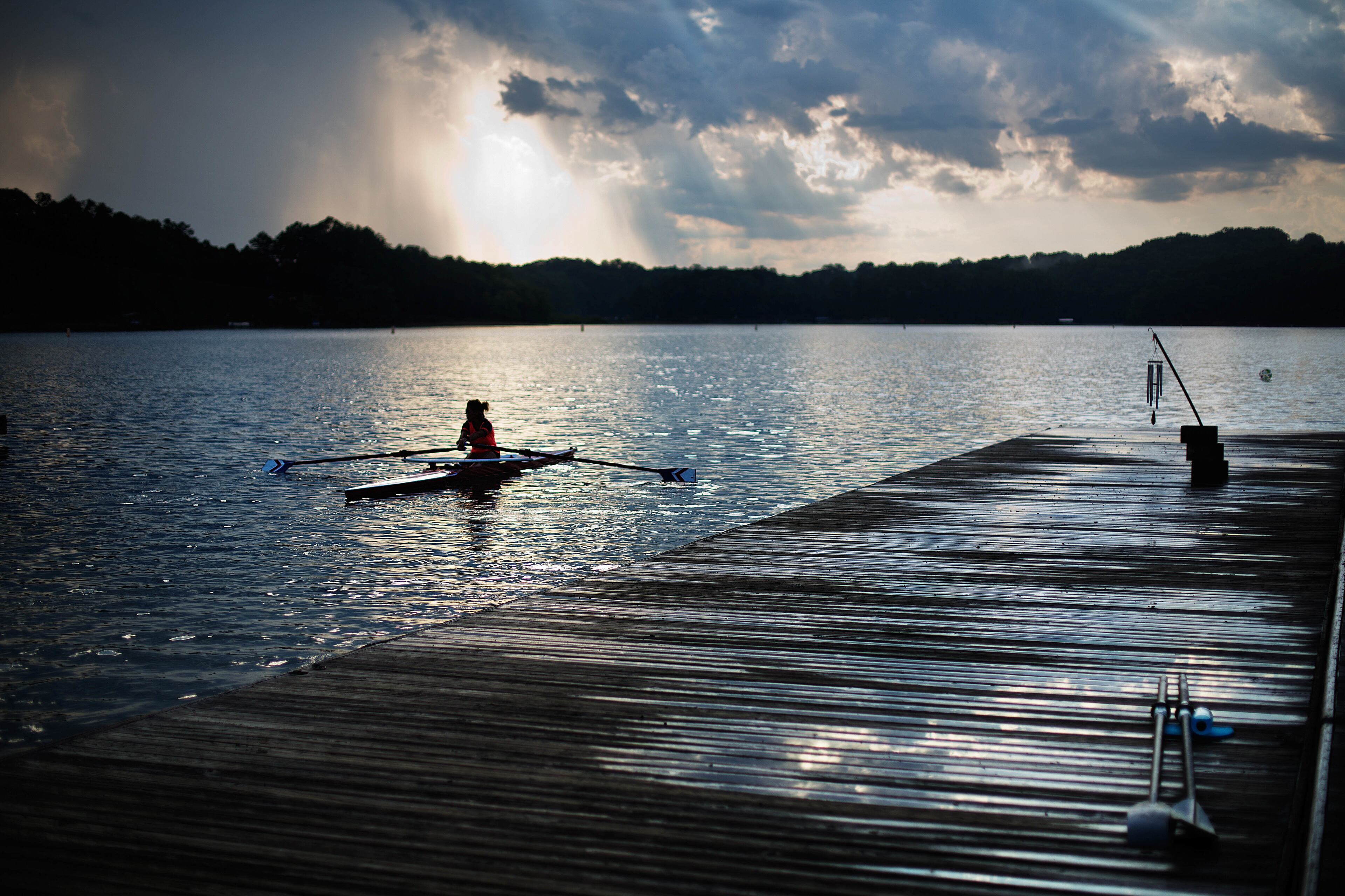 In this July 19, 2016, photo, a rower moves past the launching docks at Lake Lanier Olympic Park, home of the 1996 Summer Olympic Games rowing events, in Gainesville, Ga. This man-made lake still has its rowing facilities, which have been used for major competitions over the last two decades. This year, it hosted an Olympic qualifier for Rio and will host the Dragon Boat World Championships in 2018. (AP Photo/David Goldman)