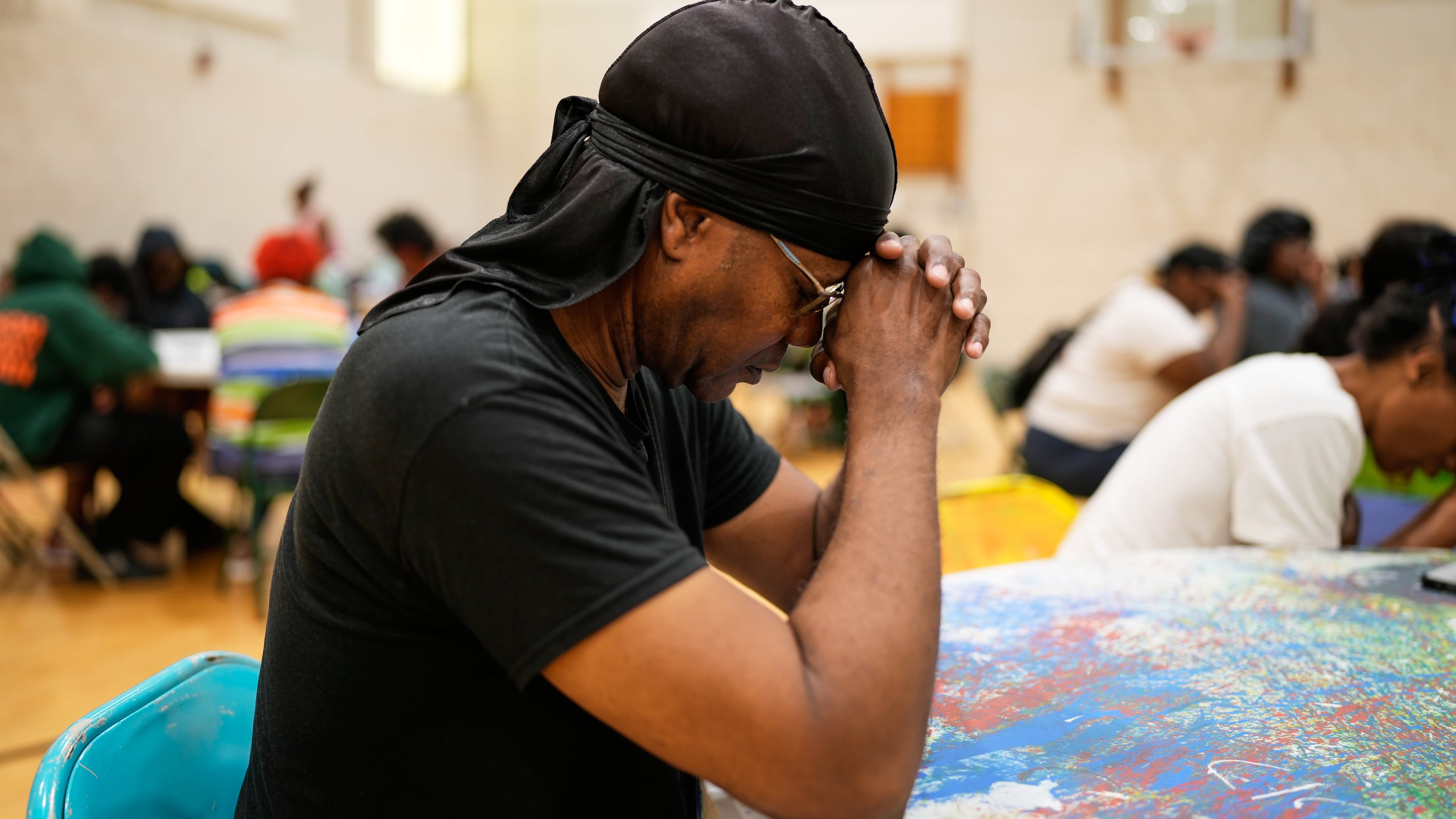 A person prays before receiving a free boxed lunch at City Life Center in Gary, Ind., Thursday, Aug. 20, 2026, more than a week after a deadly storm passed through the area. (AP Photo/Nam Y. Huh)