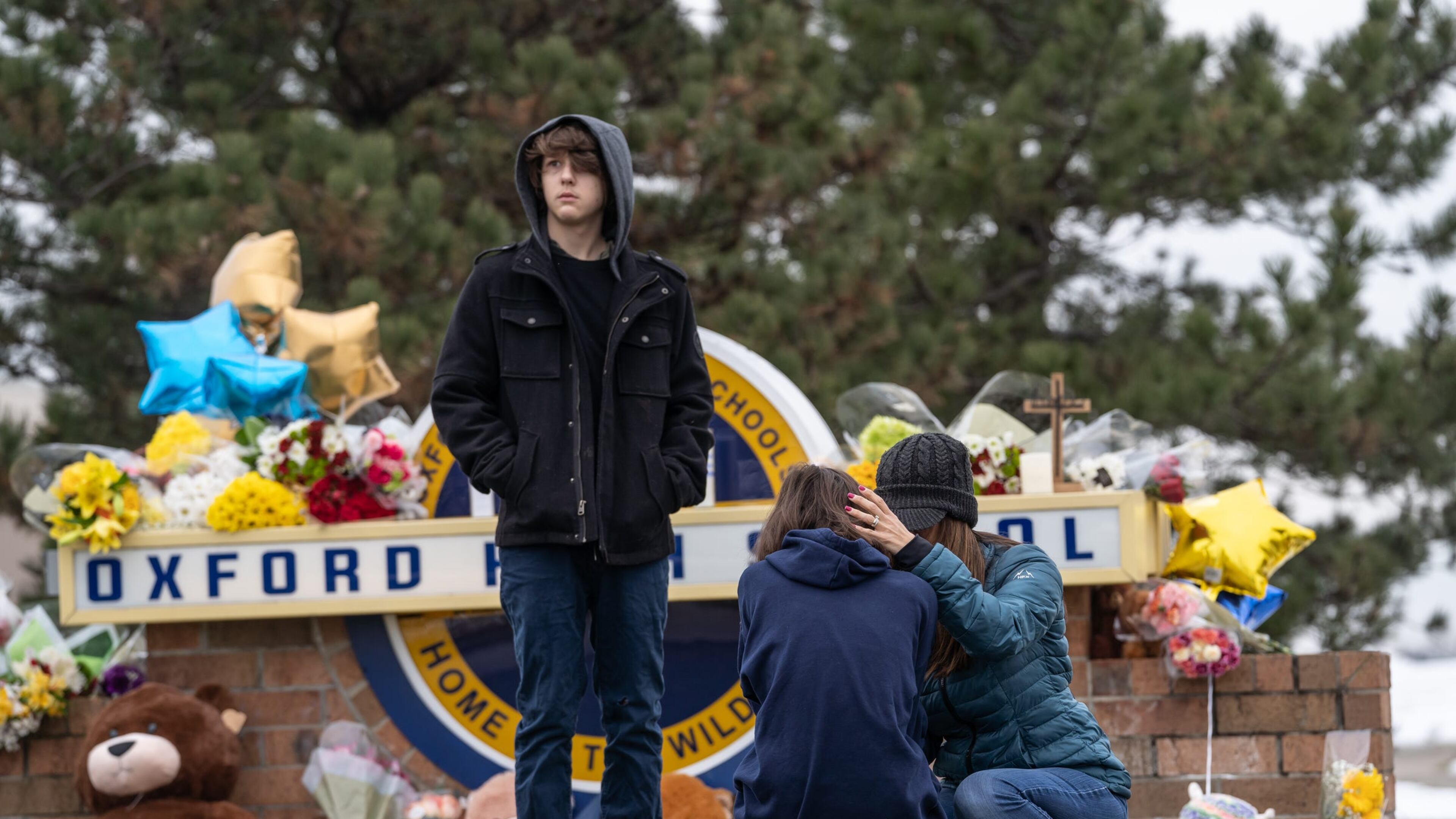 People comfort each other while visiting a memorial being built at an entrance to Oxford High School on December 1, 2021, following an active shooter situation at Oxford High School that left four students dead and multiple others with injuries. (Ryan Garza/Detroit Free Press/TNS)