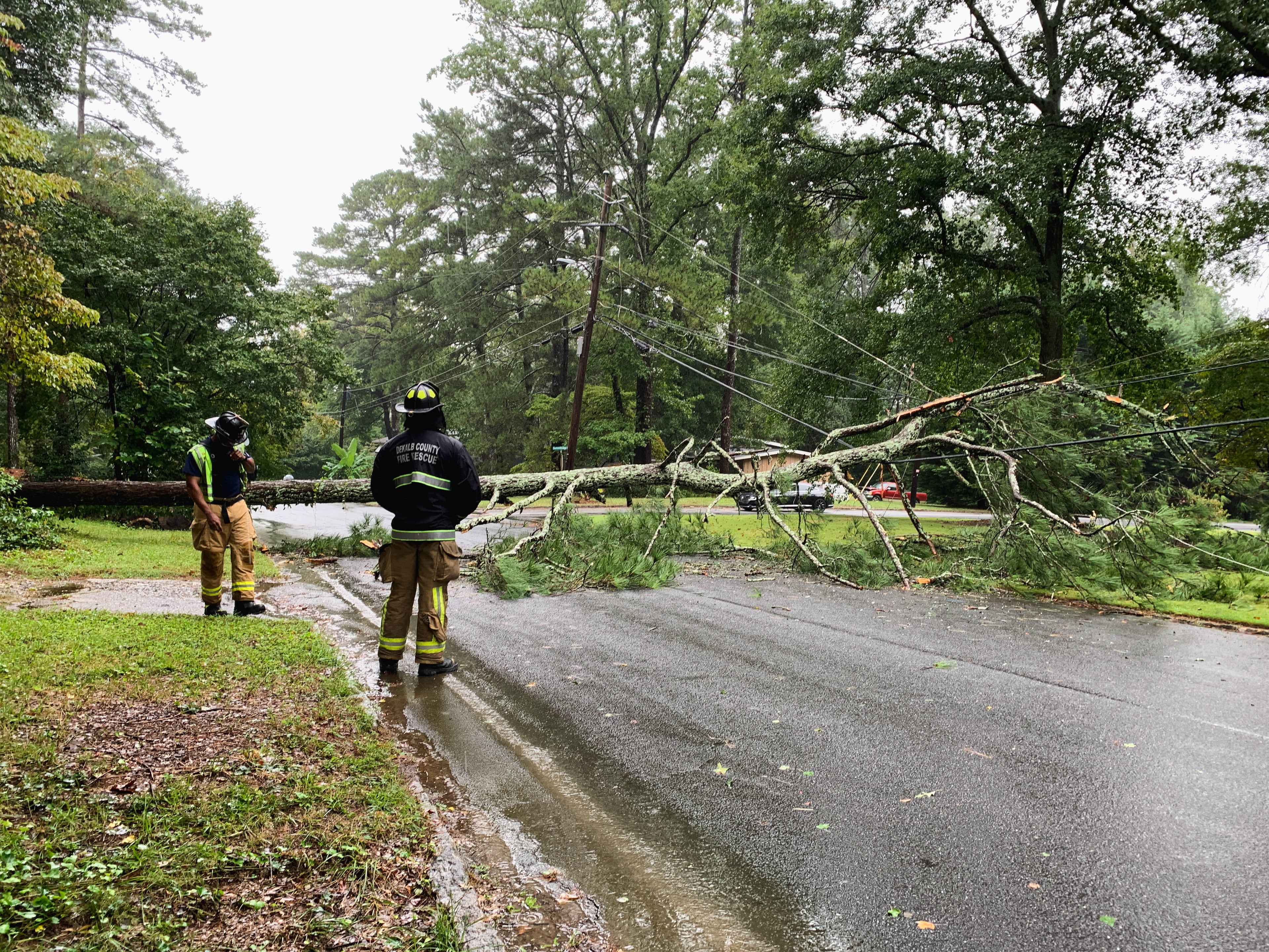 Emergency crews deal with a downed tree in the Northcrest neighborhood at the intersection of Regalwoods Dr. and Summitridge Dr. Residents are experiencing power outages and power cables lay throughout the streets. DeKalb Fire Rescue arrived on the scene within minutes of the tree falling in the city of Doraville.