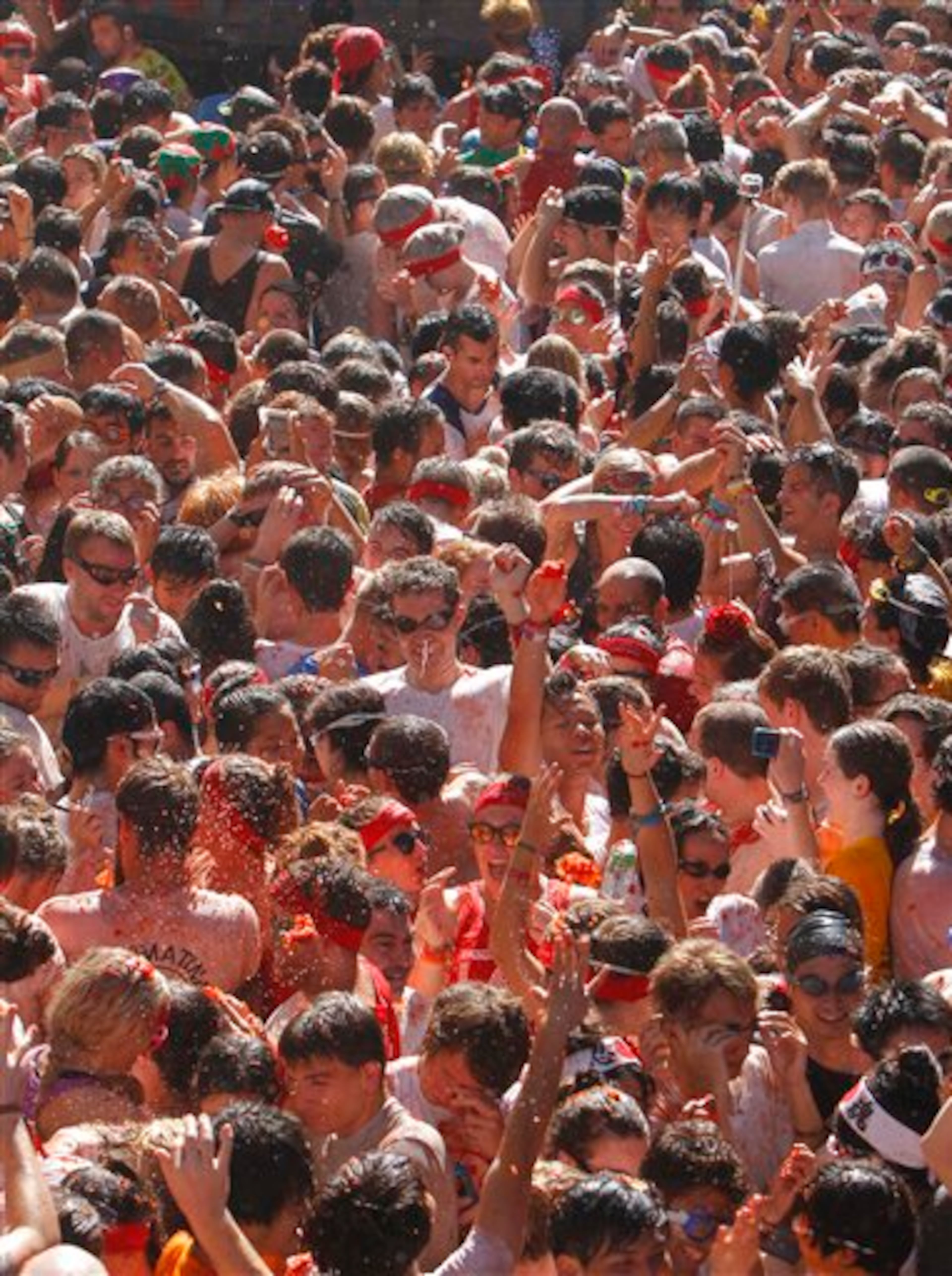 Crowds of people throw tomatoes at each other, during the annual "tomatina" tomato fight fiesta, in the village of Bunol, 50 kilometers outside Valencia, Spain, Wednesday, Aug. 27, 2014. The streets of an eastern Spanish town are awash with red pulp as thousands of people pelt each other with tomatoes in the annual "Tomatina" battle that has become a major tourist attraction. At the annual fiesta in Bunol on Wednesday, trucks dumped 125 tons of ripe tomatoes for some 22,000 participants, many from abroad to throw during the hour-long morning festivities. (AP Photo/Alberto Saiz)
