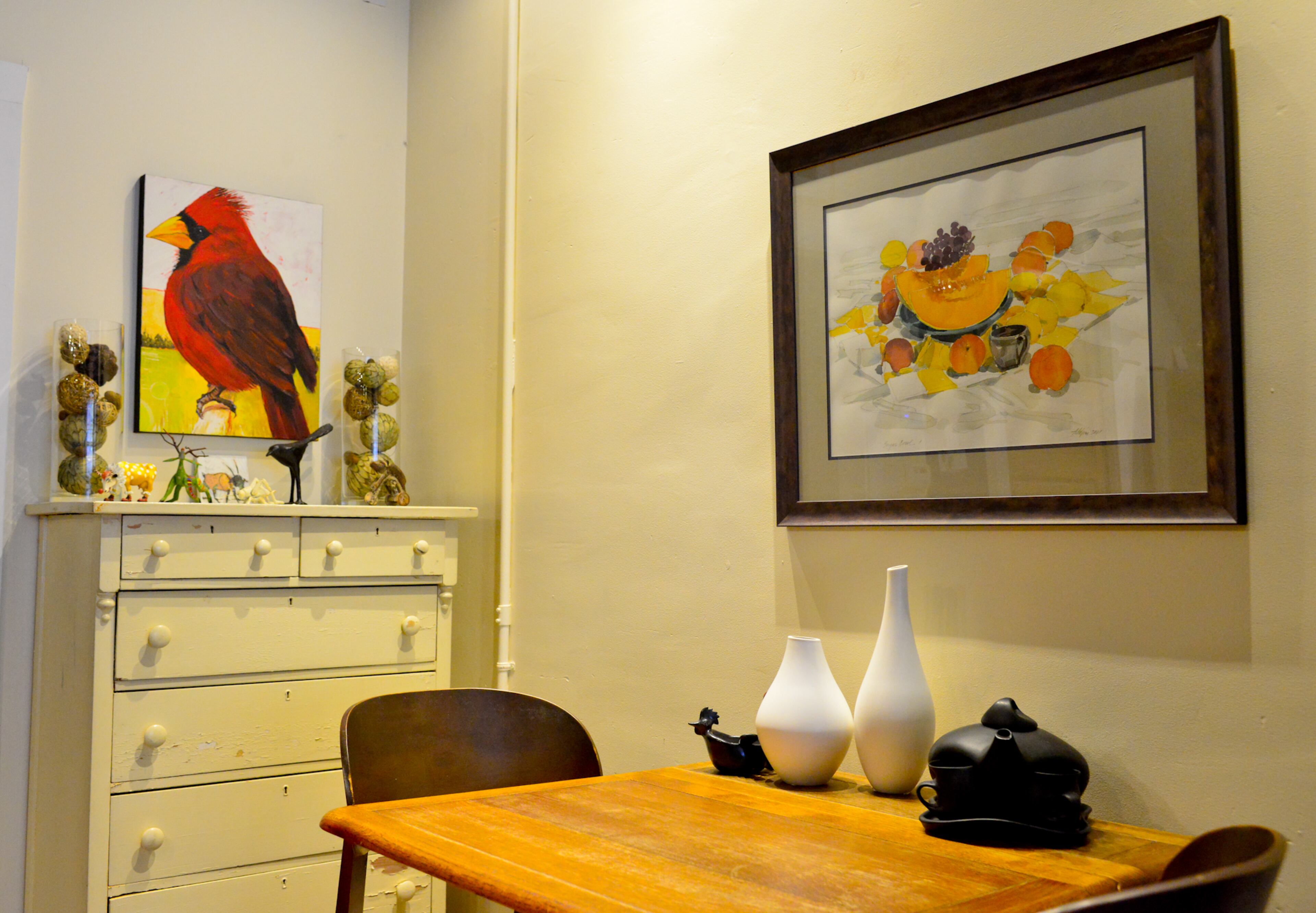 Thomas and Betsy Walsh enjoy having their coffee in the morning at the small kitchen table, which has a collection of teapots and vases and a watercolor sketch by Atlanta artist Addison Young. Next to the table, a painting of a cardinal by Janie Wright, another local artist, is a favorite piece in the home. The white dresser was another Craigslist find by Betsy Walsh.