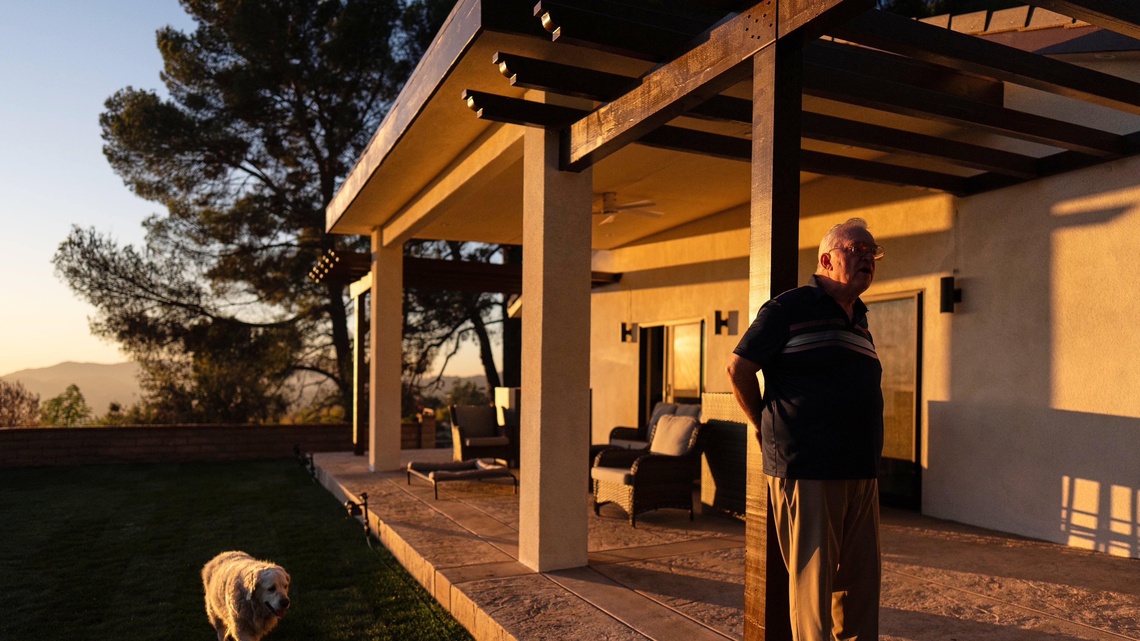 Ted Koerner, whose home was reduced to ash in the 2025 wildfires, stands on the porch of his newly rebuilt home, alongside his dog Daisy Mae, in Altadena, Calif., Dec. 11, 2025. (AP Photo/Jae C. Hong)
