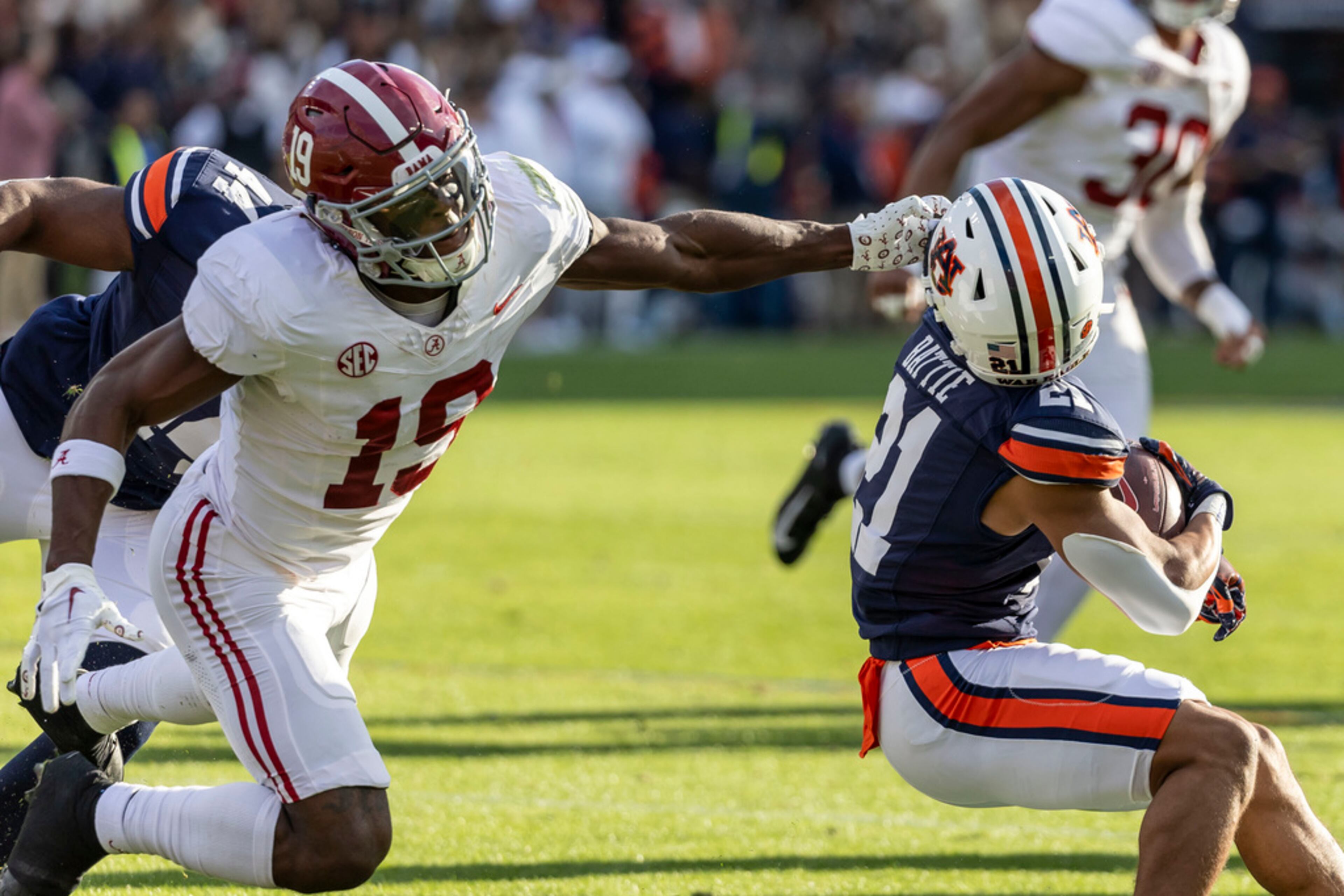 Alabama wide receiver Kendrick Law (19) gets away with a facemask against Auburn running back Brian Battie (21) on kickoff coverage during the first half of an NCAA college football game, Saturday, Nov. 25, 2023, in Auburn, Ala. (AP Photo/Vasha Hunt)