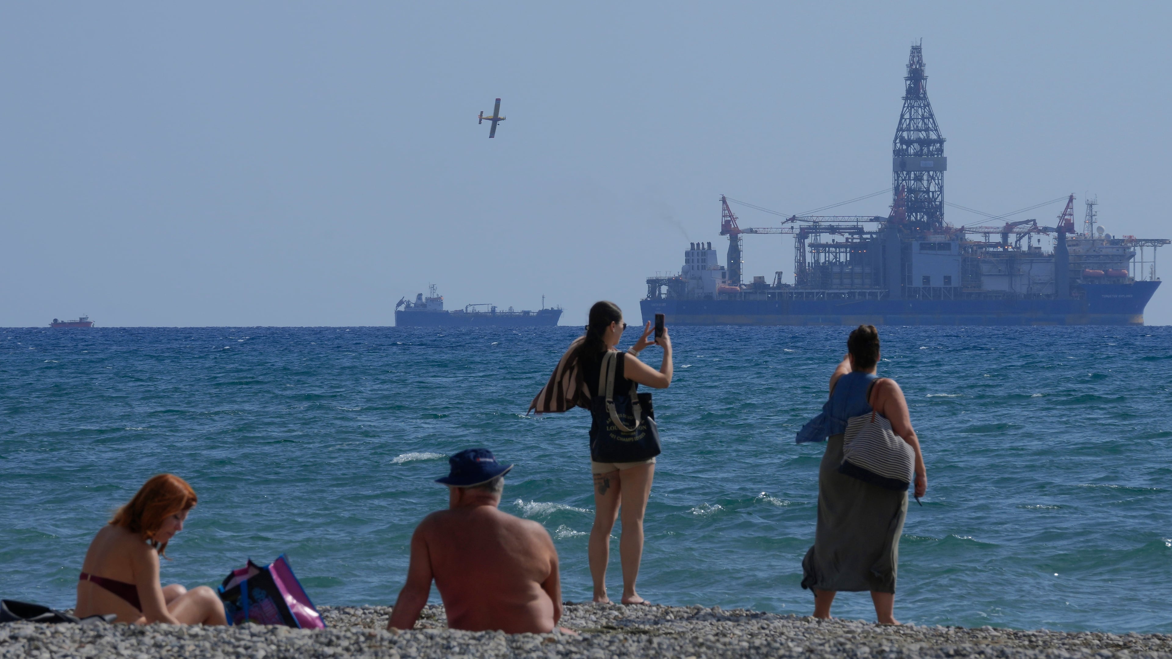 FILE - People on the beach take photos of the 'Tungsten Explored' drilling ship, in the southern coastal city of Larnaca, Cyprus, on Nov. 3, 2021. (AP Photo/Petros Karadjias, File)