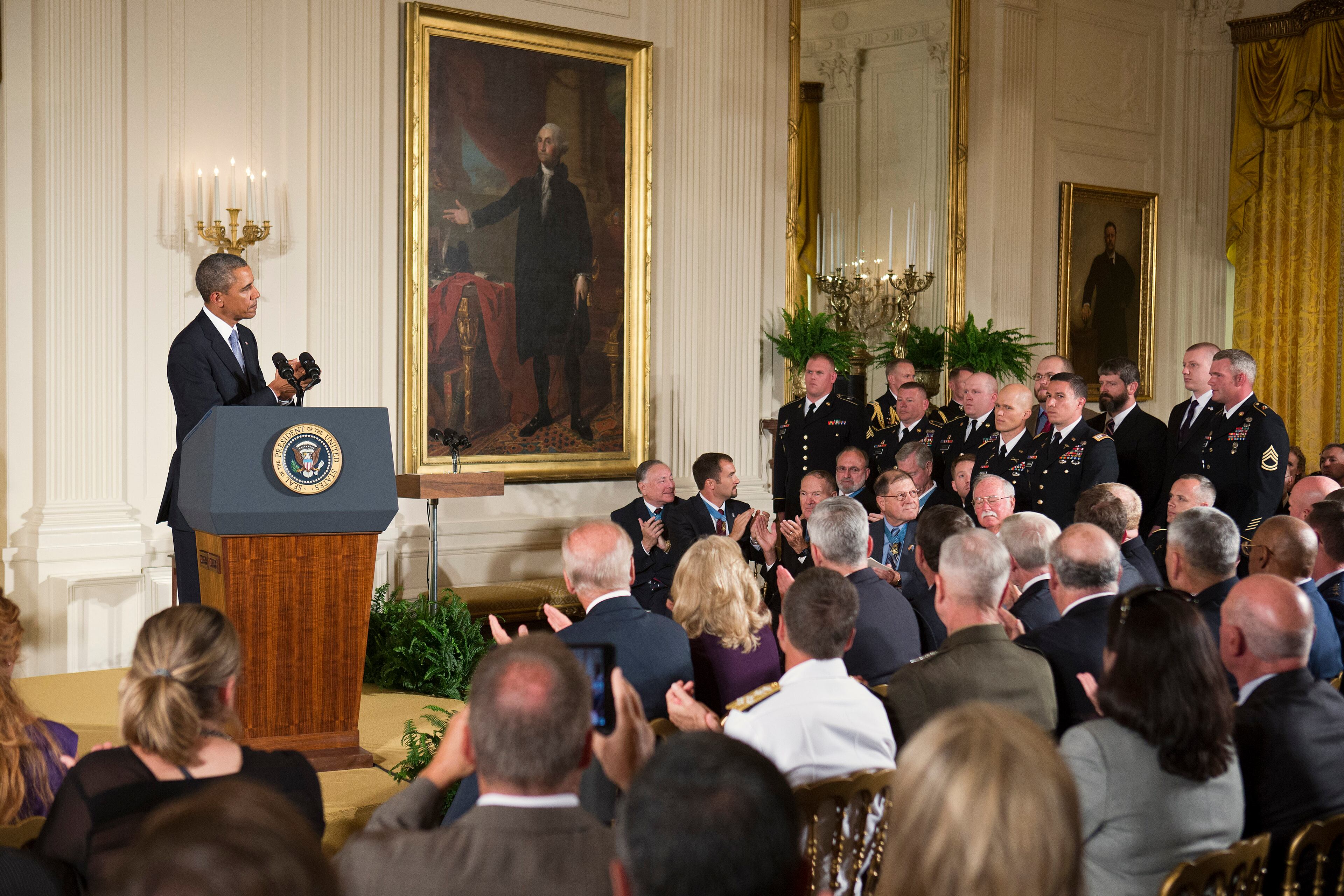 President Barack Obama acknoeledges those who served with US Army Staff Sgt. Ty M. Carter as they stand during a ceremony to award Carter the Medal of Honor for conspicuous gallantry, Monday, Aug. 26, 2013, in the East Room of the White House in Washington. Carter received the medal for his courageous actions while serving as a cavalry scout with Bravo Troop, 3rd Squadron, 61st Cavalry Regiment, 4th Brigade Combat Team, 4th Infantry Division, during combat operations in Kamdesh District, Nuristan Province, Afghanistan on Oct. 3, 2009. Carter is the fifth living recipient to be awarded the Medal of Honor for actions in Iraq or Afghanistan. (AP Photo/Jacquelyn Martin)