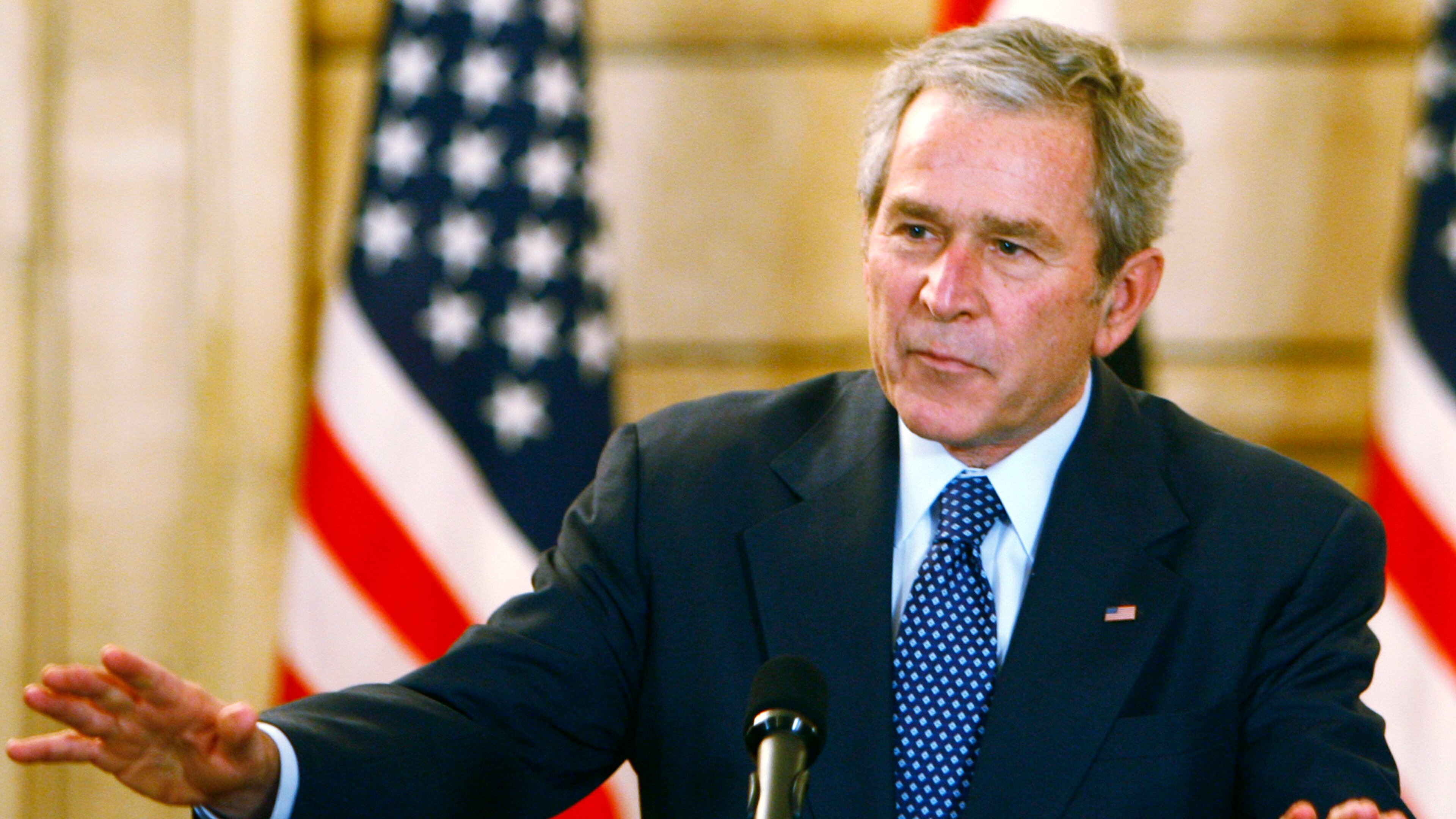 U.S. President George W. Bush reacts to calm the situation after a shoe was thrown by a reporter during a joint press conference with Iraqi Prime Minister Nuri al-Maliki (not pictured) on December 14, 2008 in Baghdad, Iraq. (Photo by Thaier al-Sudani-Pool/Getty Images)