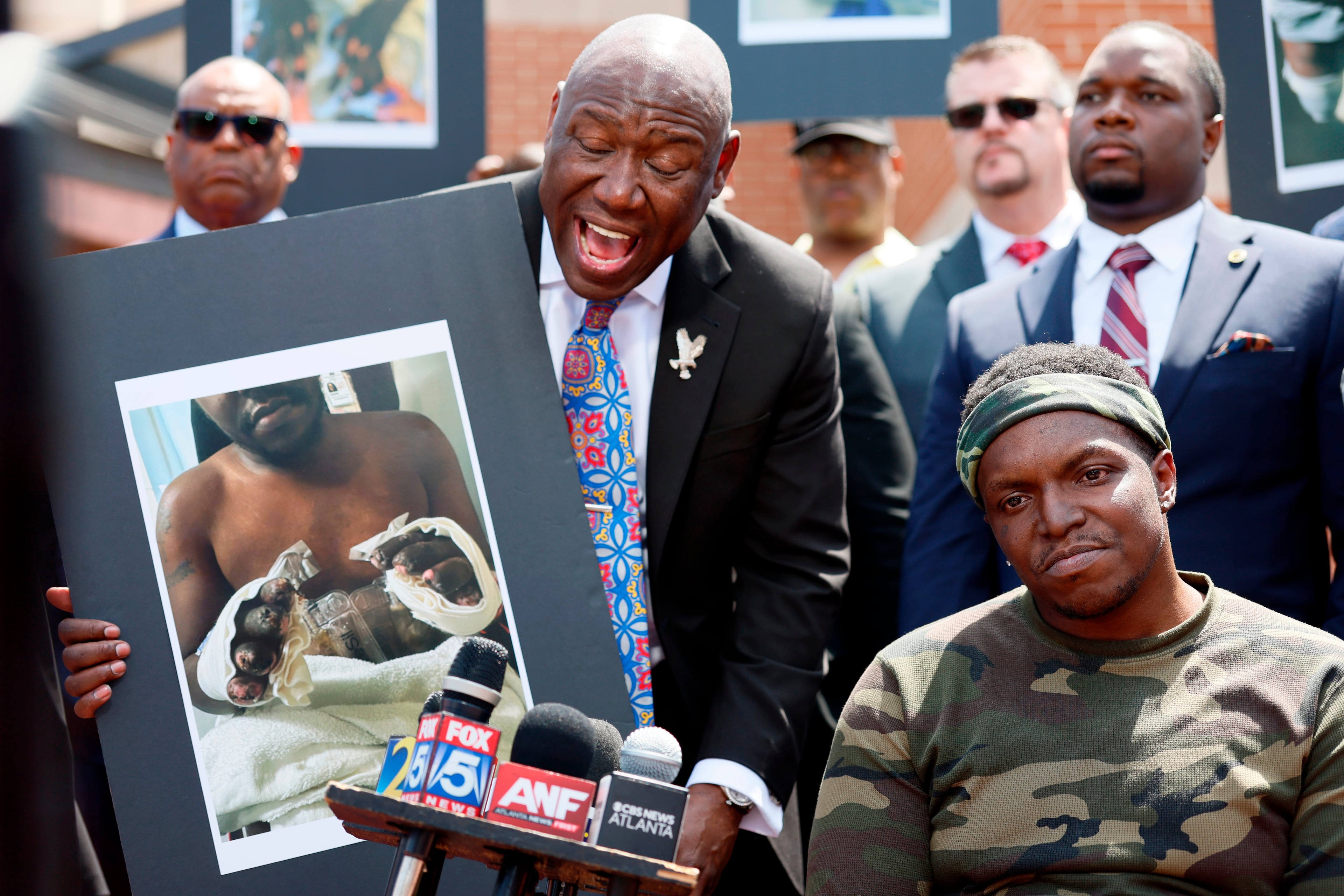 Civil rights attorney Ben Crump, left, his legal team and other supporters of Rashaad Muhammad, seated right, address the press outside the Fulton County Jail, Wednesday, April 29, 2026, in Atlanta, as he calls for a criminal investigation into alleged medical neglect of Muhammad. (Miguel Martinez/AJC)