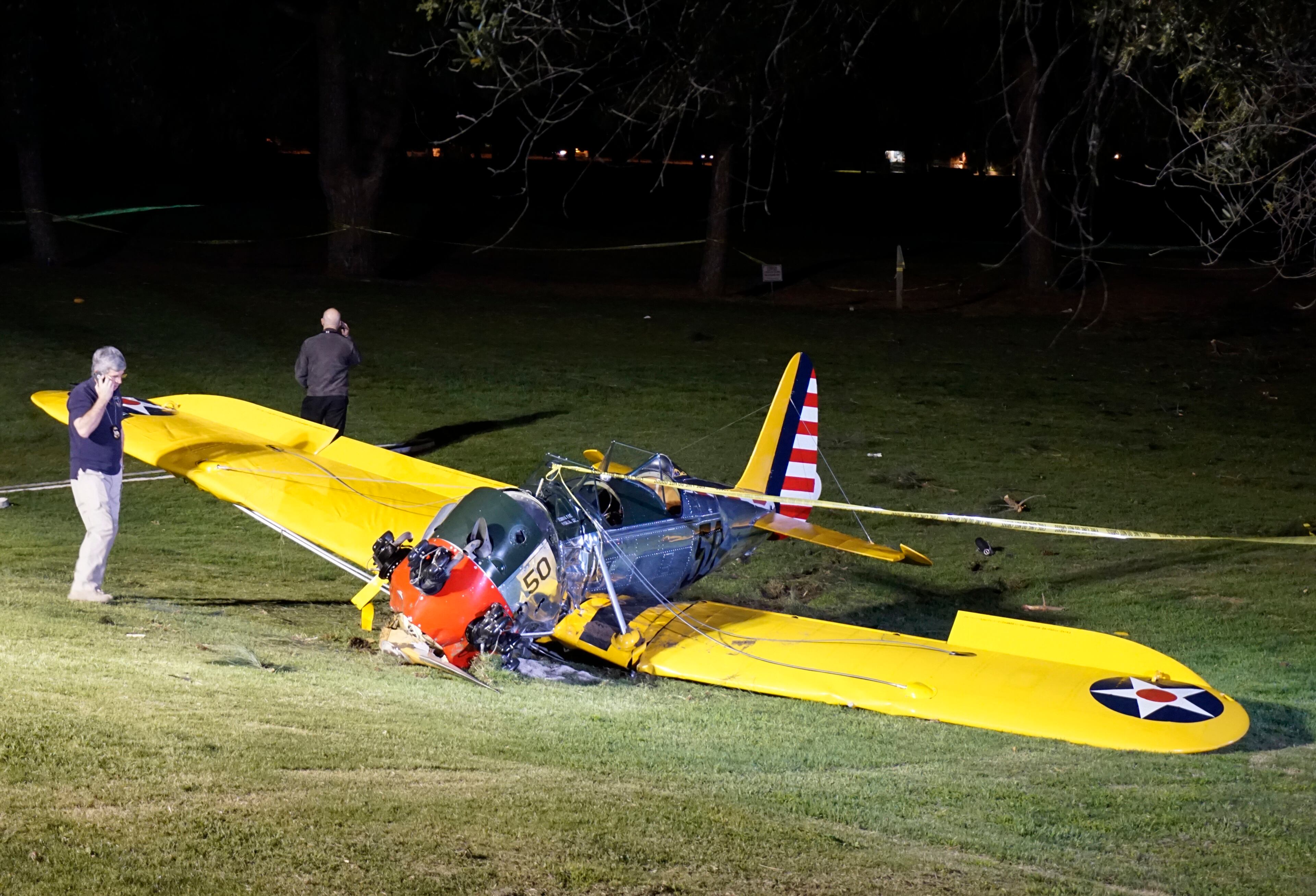 National Transportation Safety Board investigator Patrick Jones, left, stands by the small plane that crash-landed on the Penmar Golf Course in the Venice area of Los Angeles, Thursday, March 5, 2015. Harrison Ford crash-landed the airplane shortly after taking off from a nearby airport and reporting engine problems. (AP Photo/Damian Dovarganes)