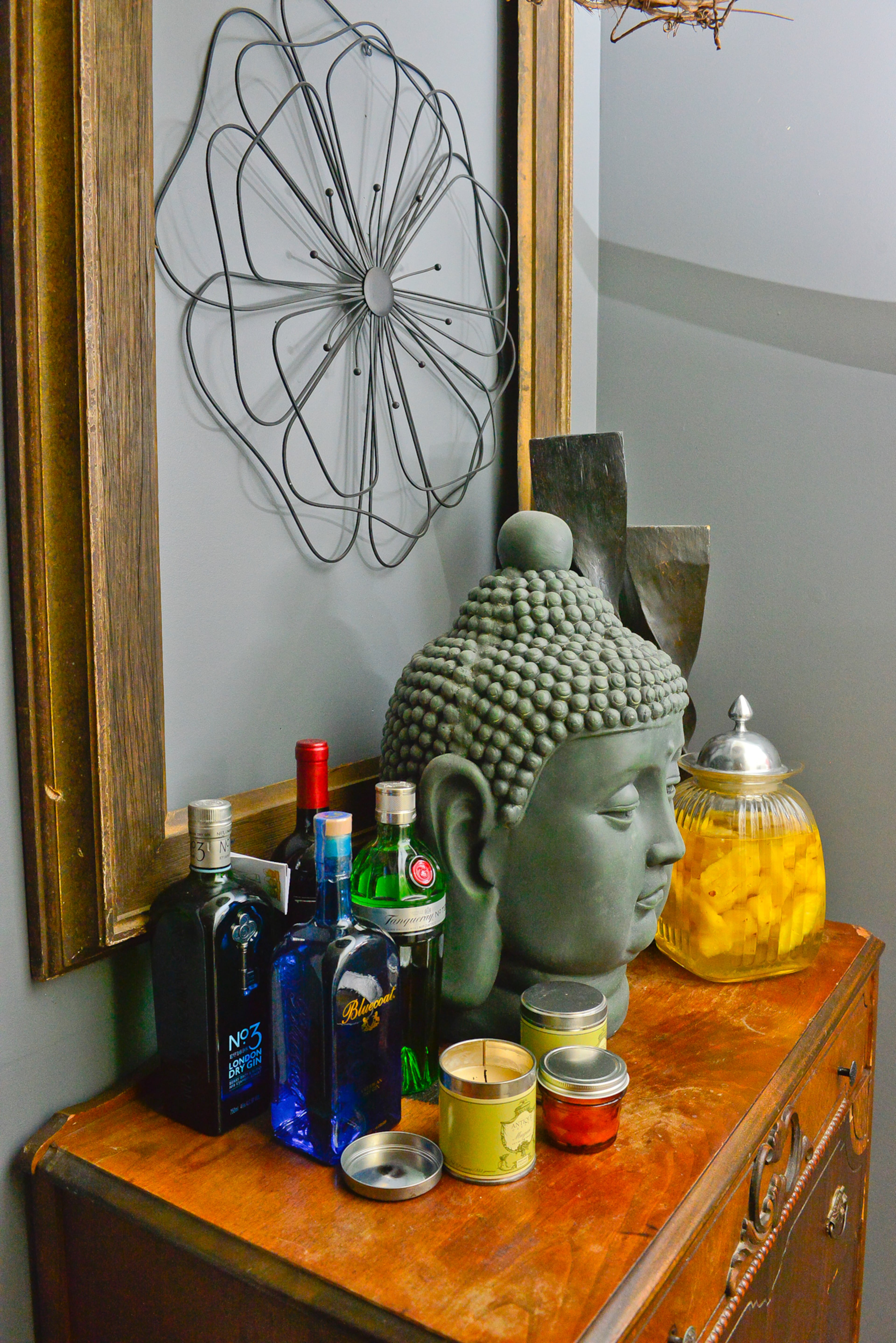 An antique wooden chest makes a perfect pit stop for a drink. A large Buddha bust tops the makeshift dry bar and complements the Sherwin-Williams Fog Grey walls in the foyer.