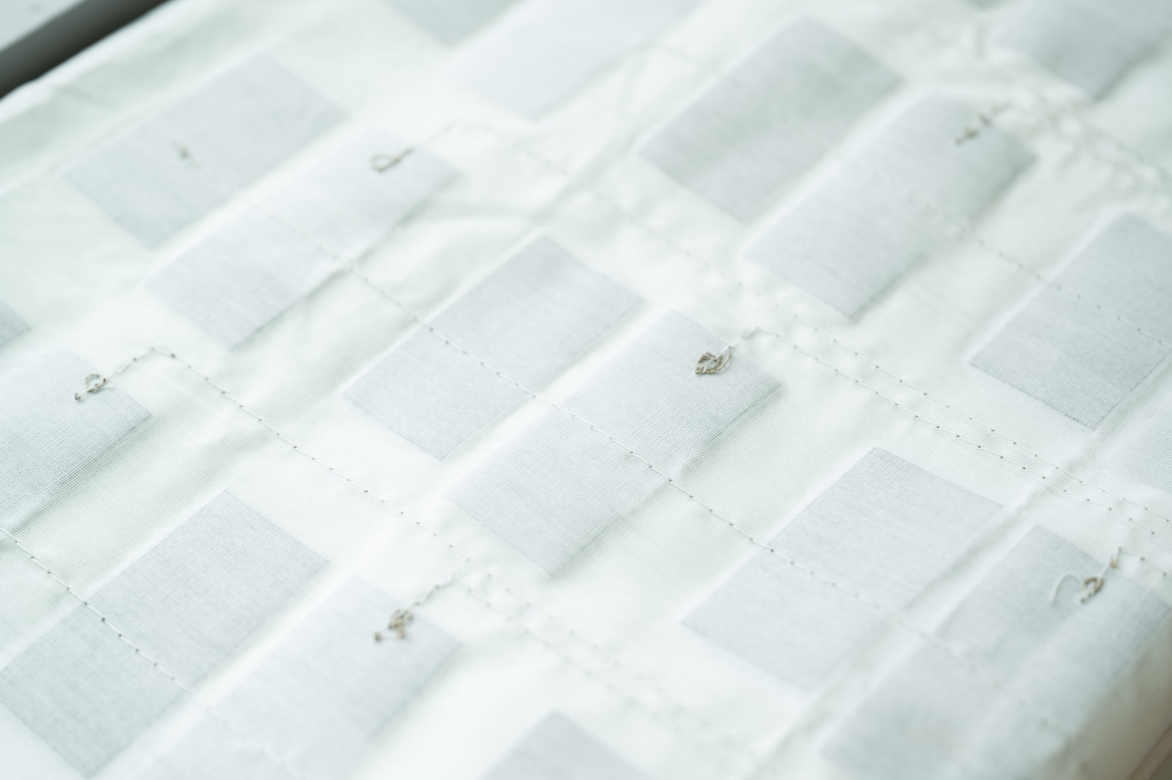 A sheet embedded with lightweight fabric sensors sits atop the crib mattress and under the fitted crib sheet. The sensors, which are flexible and reusable after being sanitized, send data to an app that monitors a patient’s condition. (Courtesy of Georgia Tech)