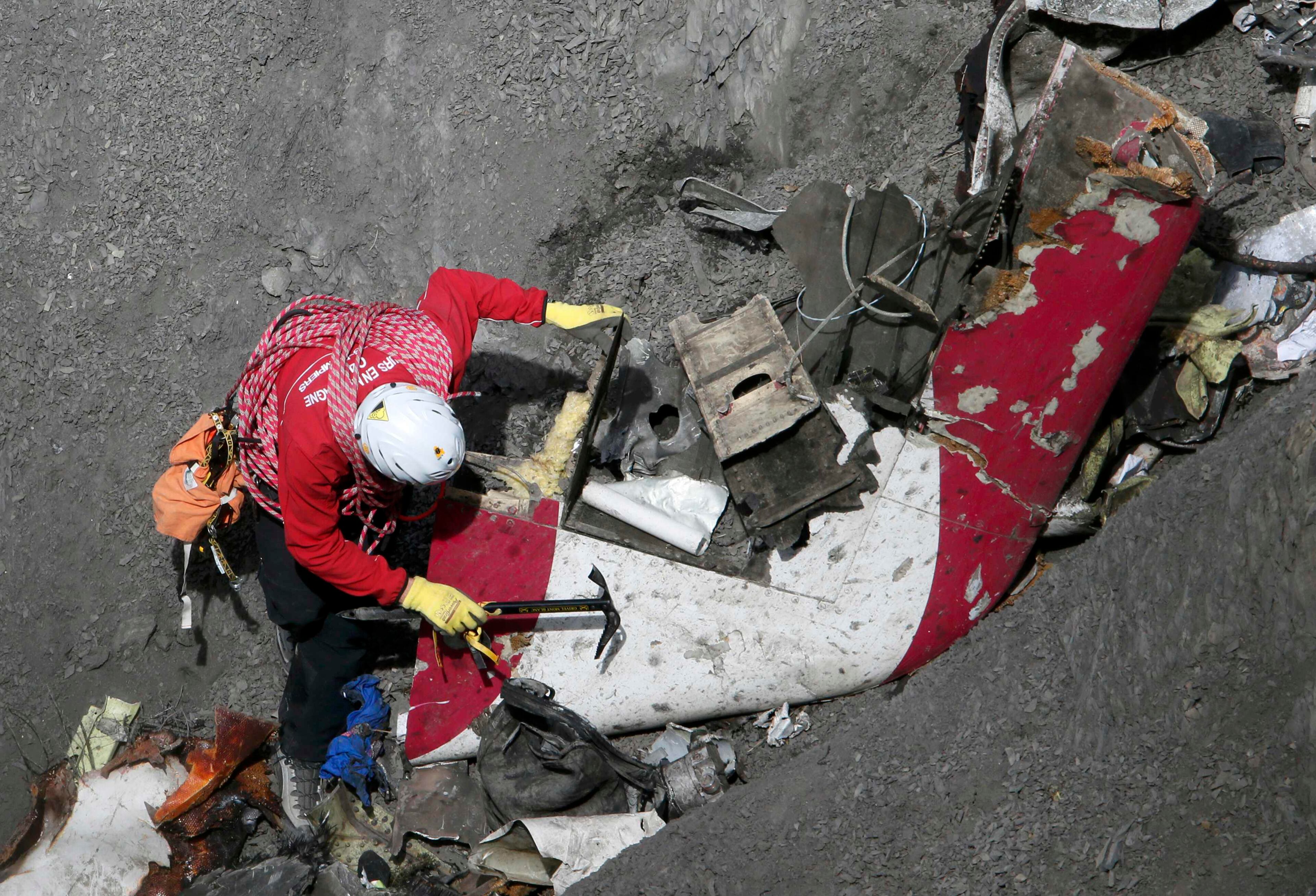 A French rescue worker inspects the remains of the Germanwings Airbus A320 at the site of the crash, near Seyne-les-Alpes, French Alps March 29, 2015. The co-pilot suspected of deliberately crashing a passenger plane in the French Alps told his girlfriend he was in psychiatric treatment, and that he was planning a spectacular gesture that everyone would remember, the German daily Bild reported on Saturday. REUTERS/Gonzalo Fuentes