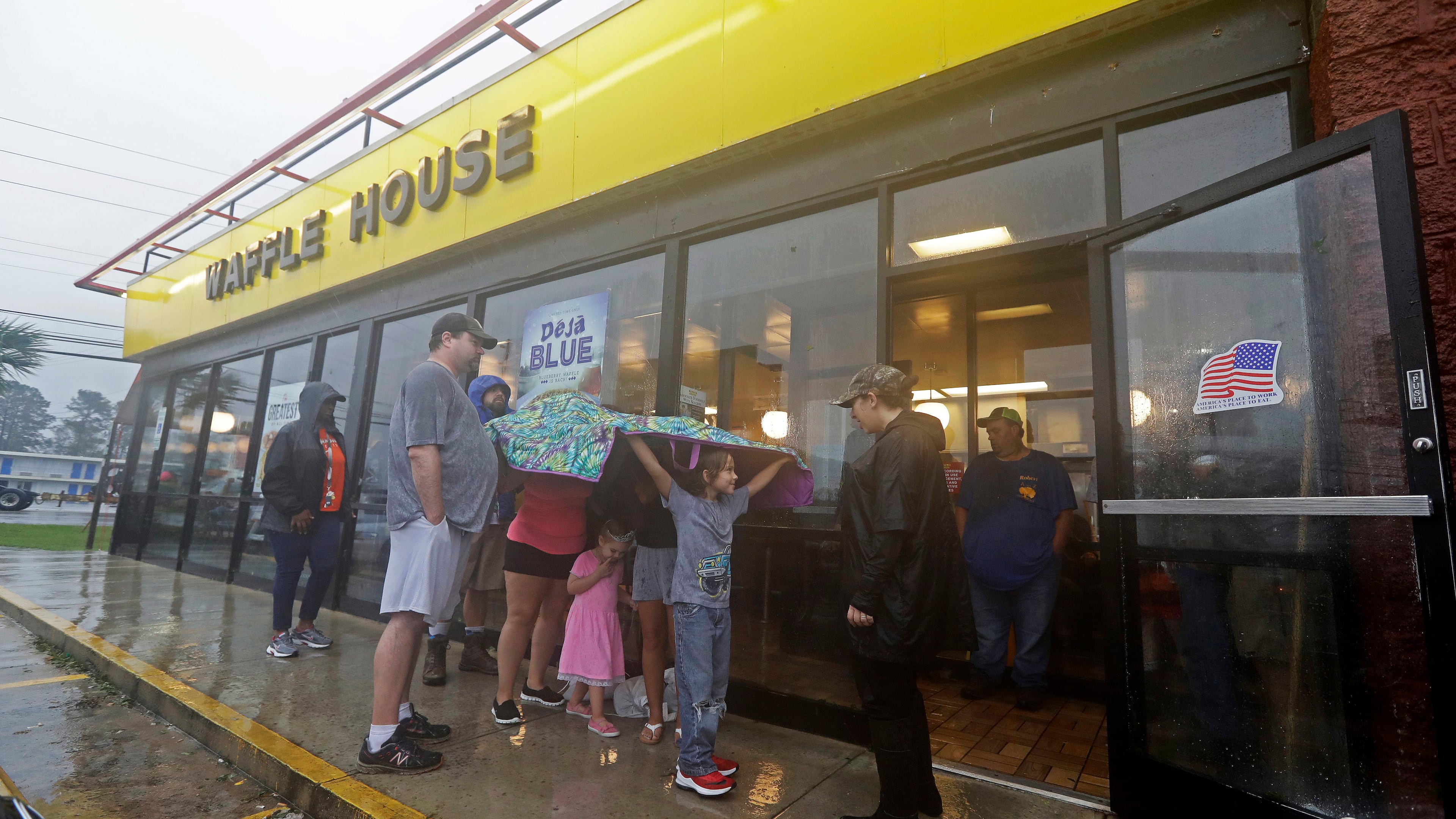 FILE - Luke Churchill, left, stands with his wife Mary and their children, Katie, Liam and Raighan, as they wait in the rain outside an open Waffle House restaurant in Wilmington, N.C., after Hurricane Florence traveled through the area on Sept. 16, 2018. (AP Photo/Chuck Burton, File)