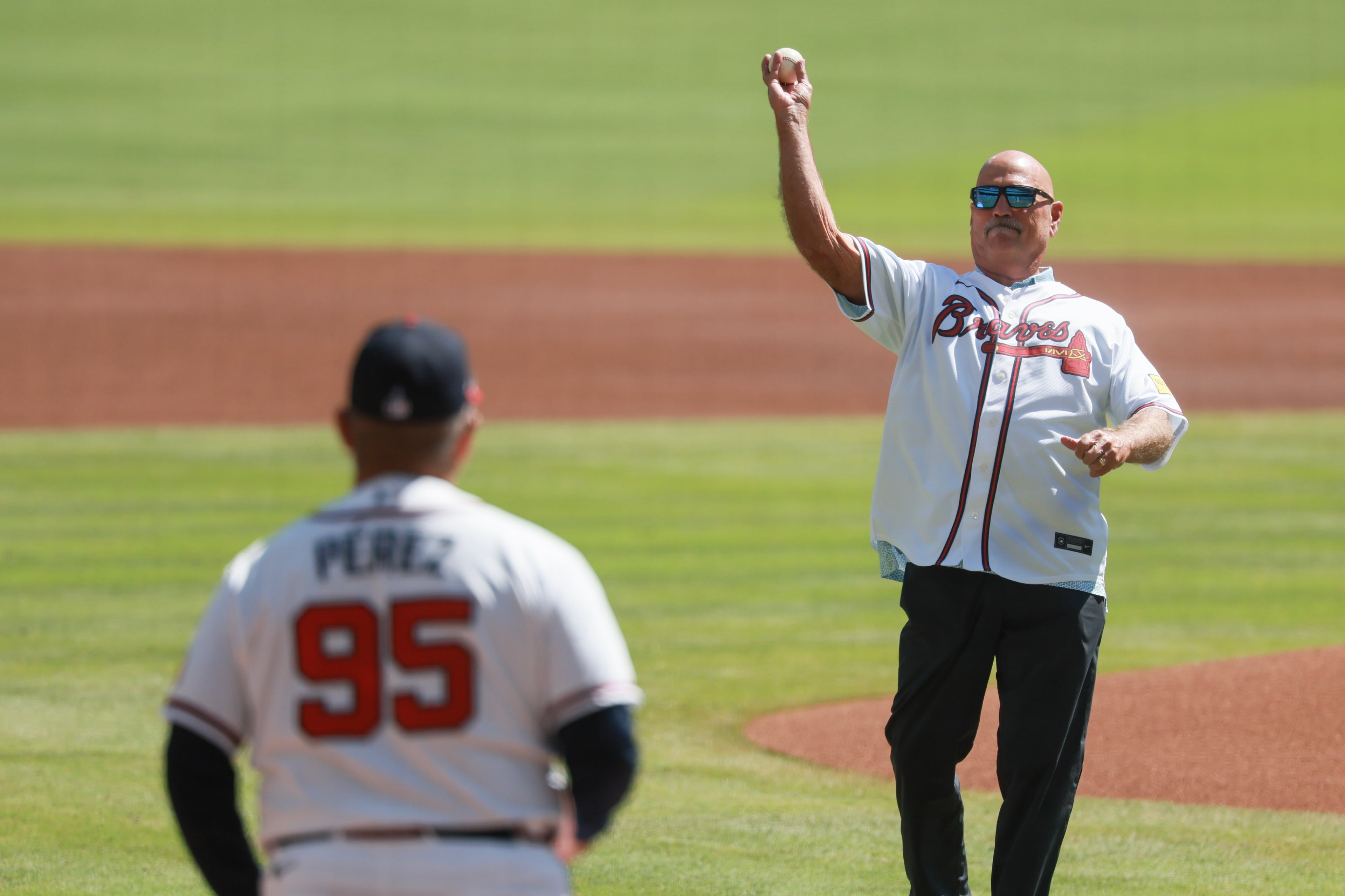 Former Atlanta Braves manager Brian Snitker, right, throws out the ceremonial first pitch to Eddie Perez, left, before Game 1 of a MLB National League Wild Card playoff series between the Atlanta Braves and the Philadelphia Phillies, Tuesday, Sept. 29, 2026, in Atlanta. (Jason Getz/AJC)