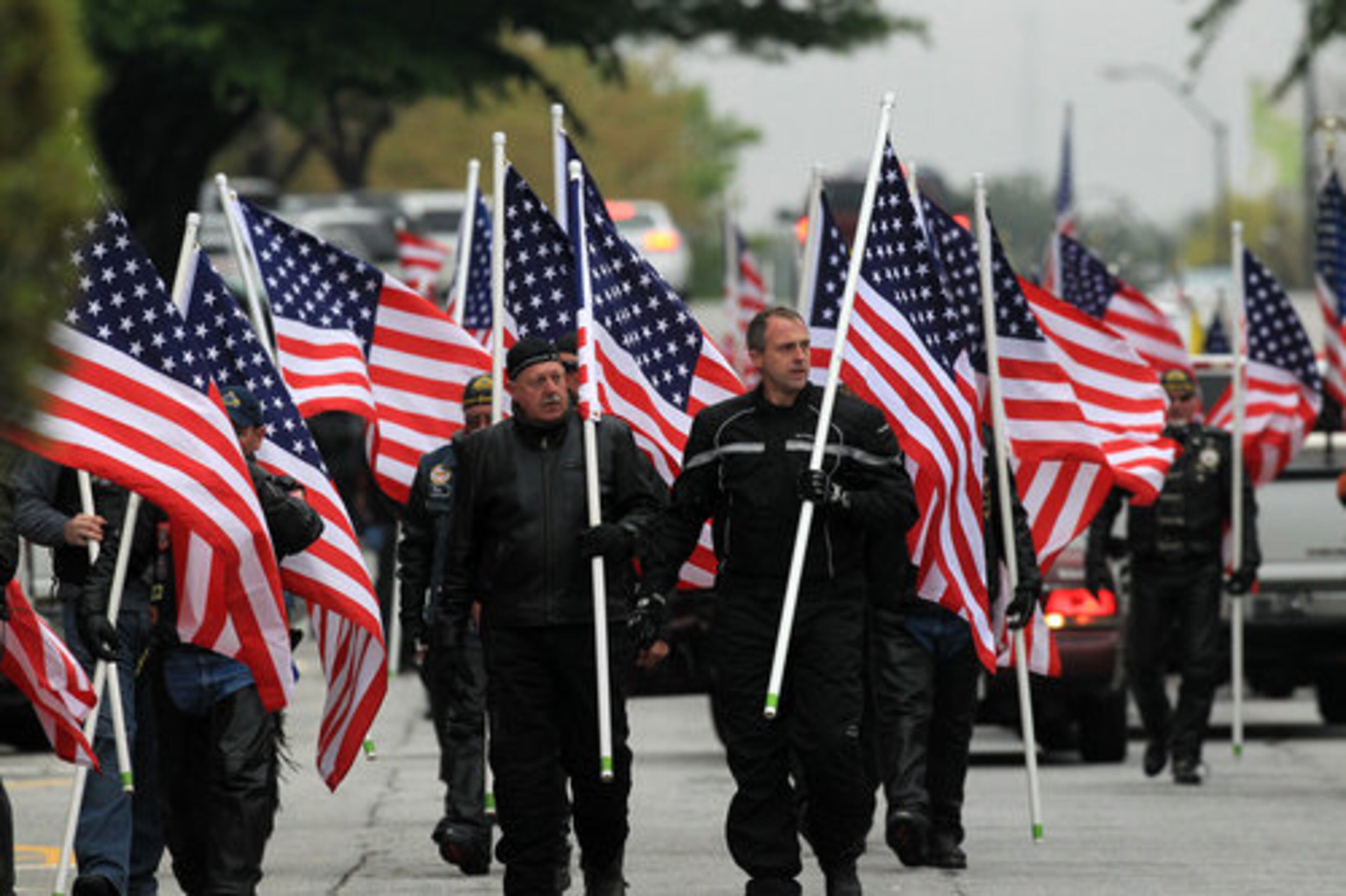 Members of the Patriot Guard walk down the street with American flags for the funeral of slain Athens Senior Police Officer Elmer "Buddy" Christian at the Classic Center Theatre in Athens on Sunday, March 27, 2011.