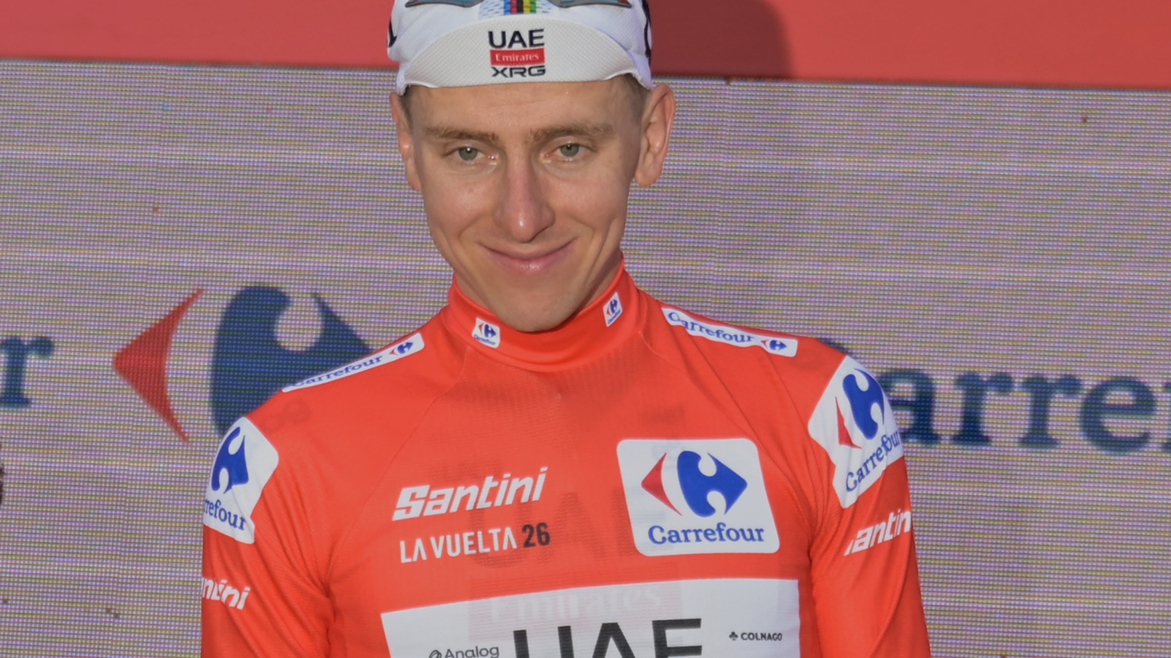 Slovenia's Tadej Pogacar, wearing the overall leader's red jersey celebrates on the podium after the second stage of the La Vuelta cycling race, with start in Monaco and finish in Manosque, France, Sunday, Aug. 23, 2026. (AP Photo/Philippe Magoni)