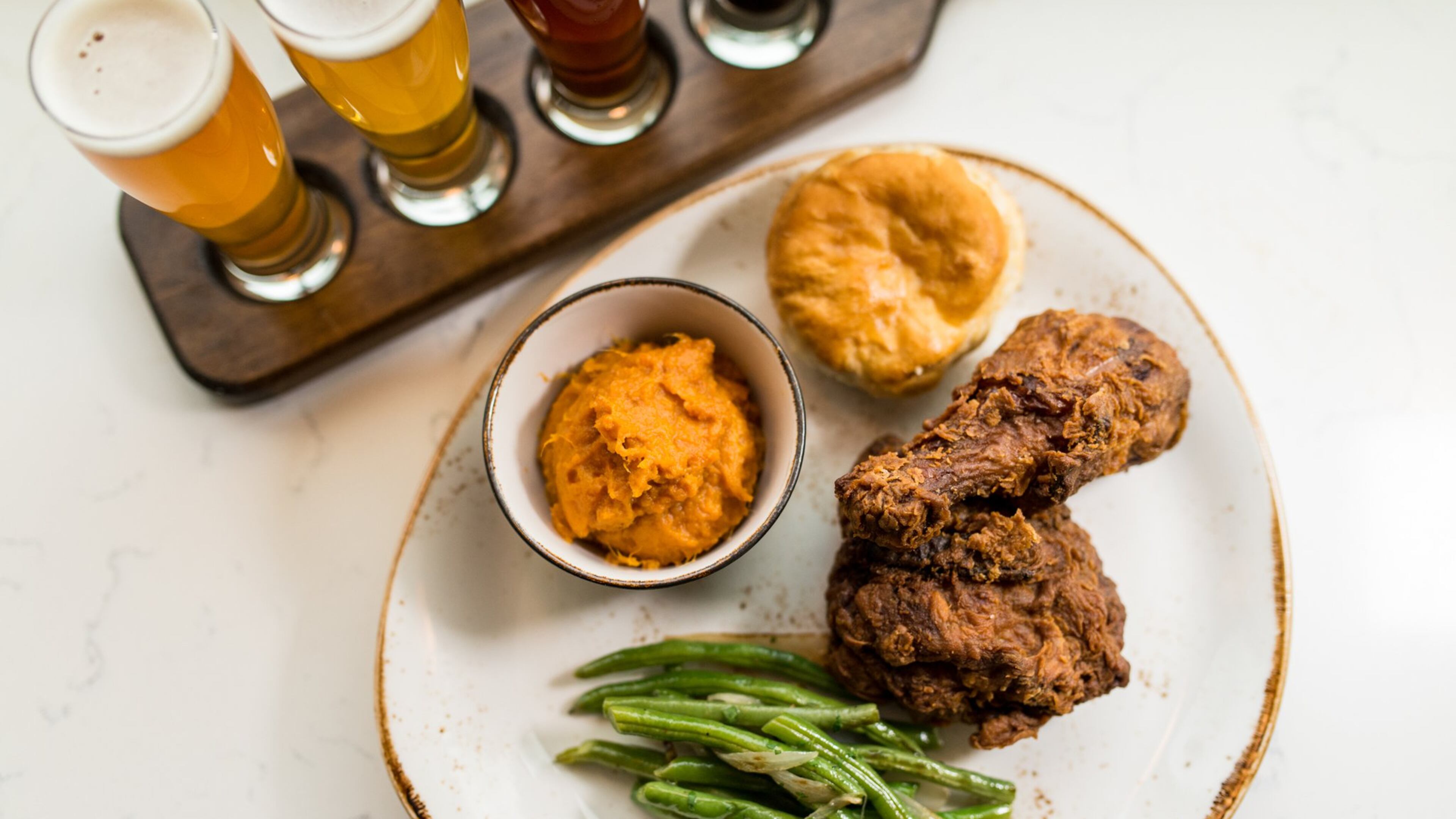 Southern fried chicken with molasses biscuit, braised green beans, and sweet potato mash and a local beer flight at Chicken + Beer. / Photo credit- Mia Yakel.